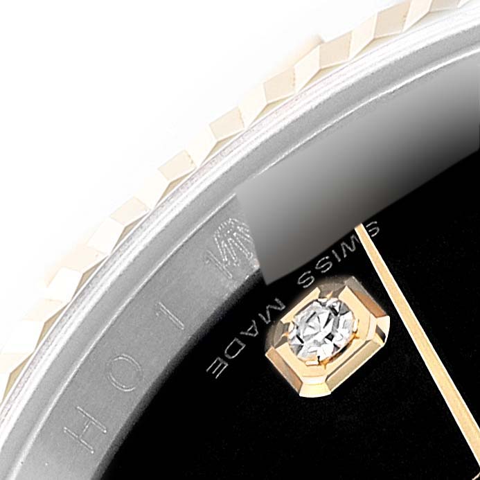 This close-up image shows a portion of the dial and diamond hour marker of a Rolex Datejust 116233 Men's Steel and Gold (two tone) Black Dial 116233 Men's Steel and Gold (two tone) Black Dial watch, along with part of the fluted bezel.