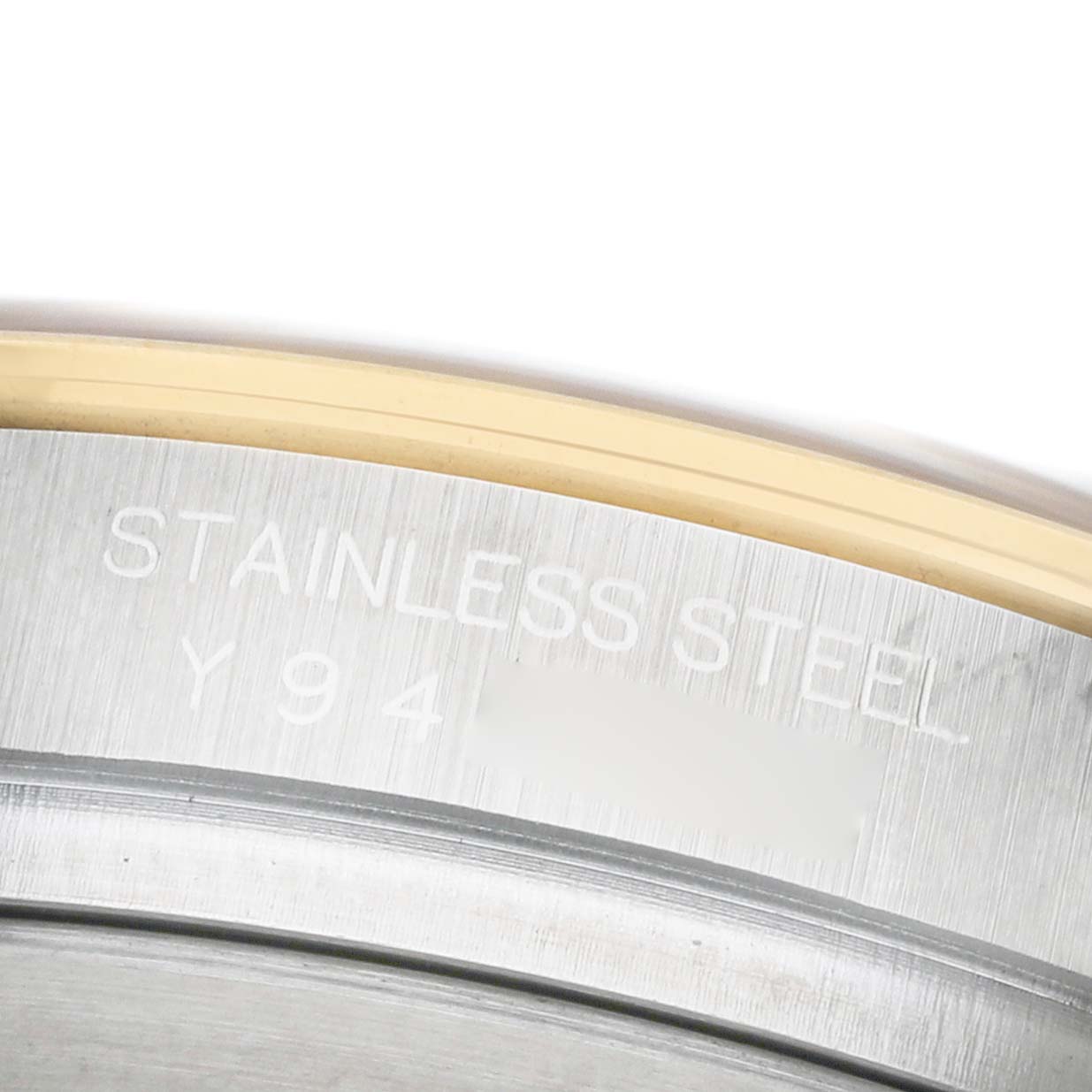 The image shows a close-up of the case side engraving on a Rolex Daytona 116523 Men's Steel and Gold (two tone) Black Dial, highlighting the "STAINLESS STEEL" marking.