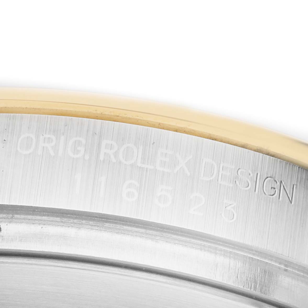 The image shows a close-up of the case side of a Rolex Daytona 116523 Men's Steel and Gold (two tone) Black Dial, featuring engraved model details.