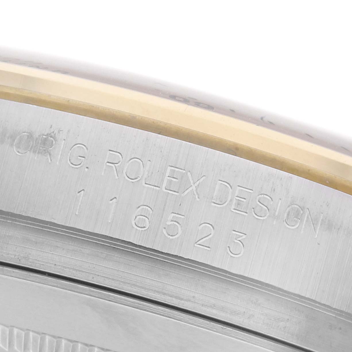 The image shows a close-up of the side of a Rolex Daytona 116523 Men's Steel and Gold (two tone) White Dial 116523 Men's Steel and Gold (two tone) White Dial case with engraved branding and serial number details.