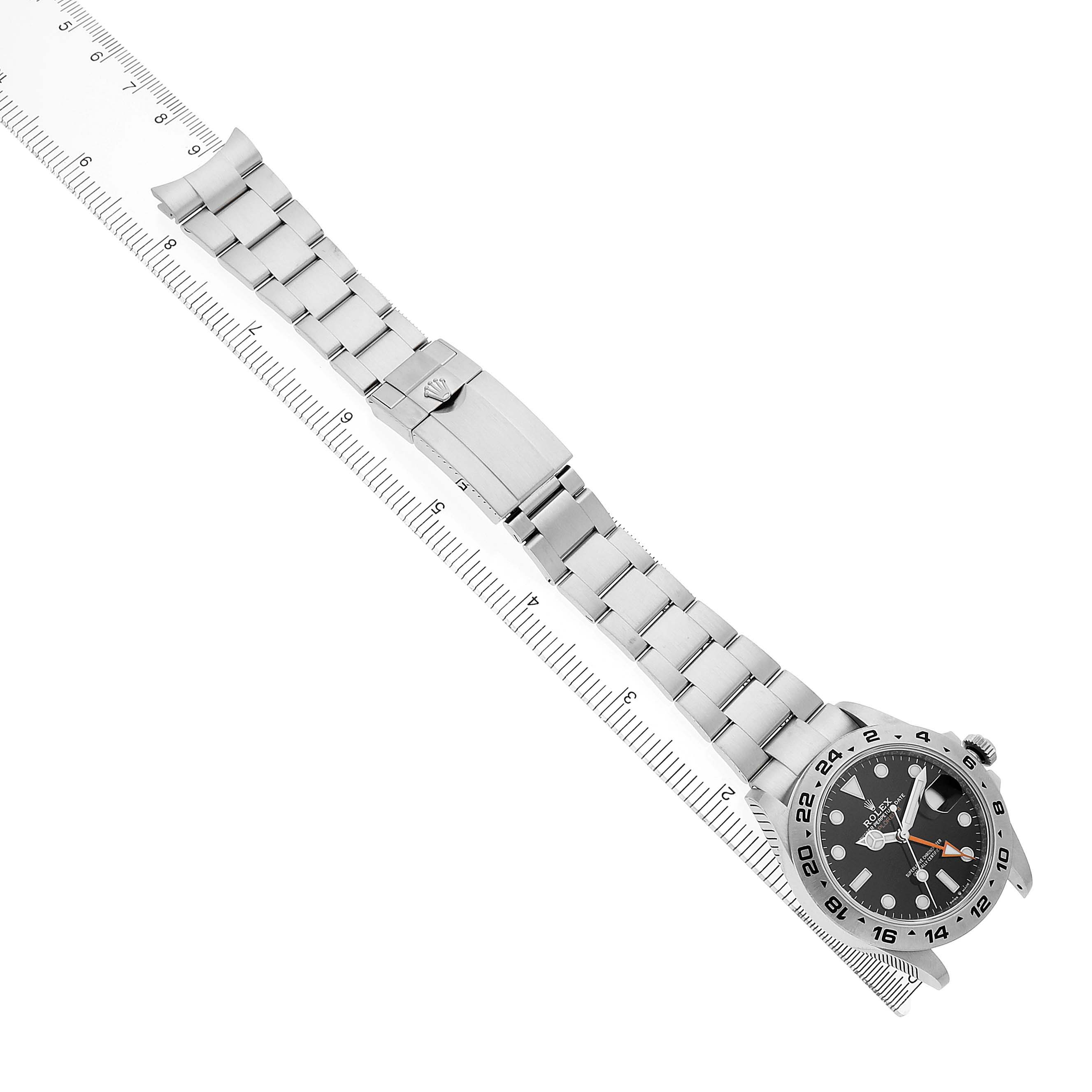 The Rolex Explorer 226570 Men's Stainless Steel Black Dial watch is shown diagonally with a full bracelet and clasp visible alongside a ruler for scale.