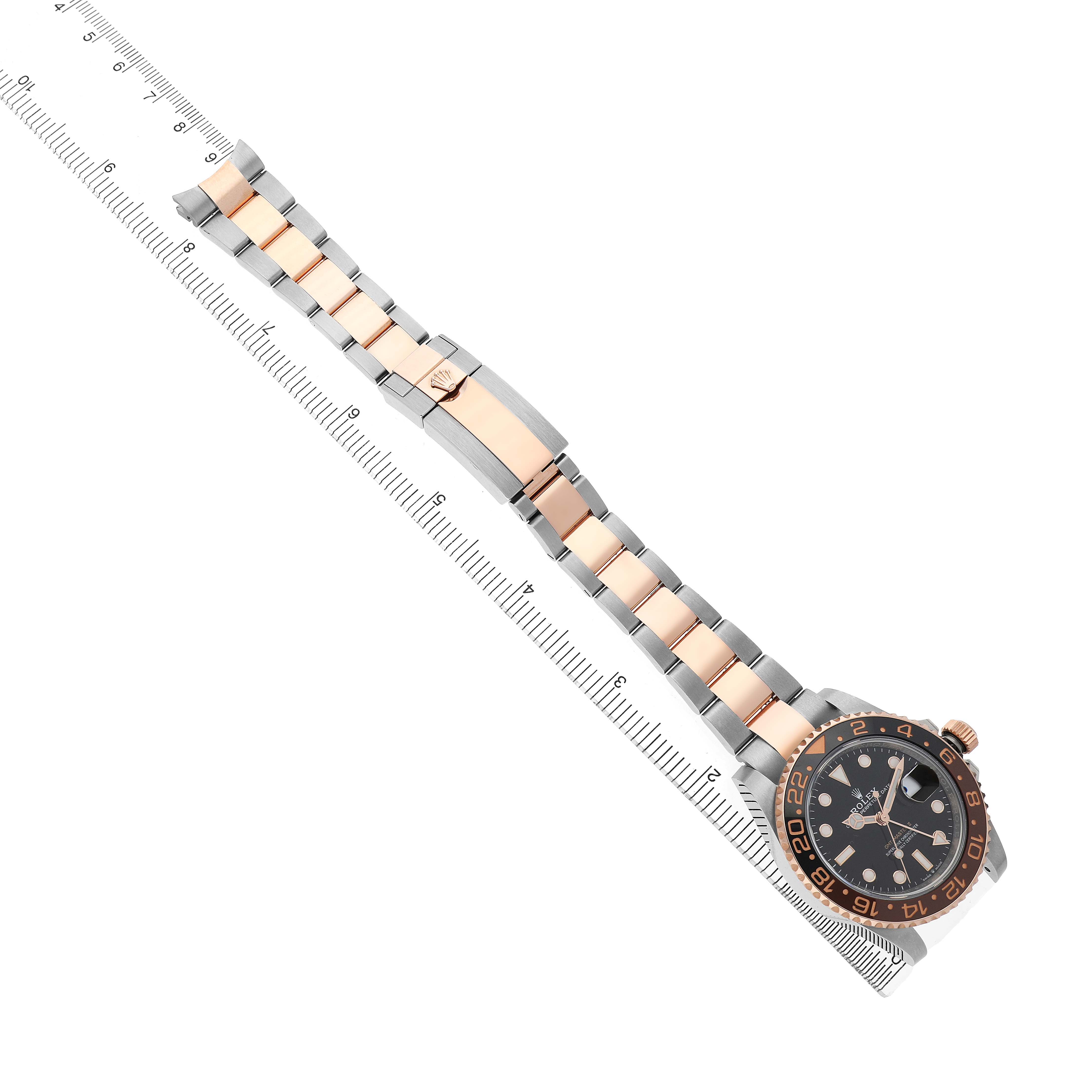 The image shows a top view of a Rolex GMT-Master 126711CHNR Men's Steel and Gold (two tone) Black Dial watch, focusing on the face and entire bracelet alongside a ruler.