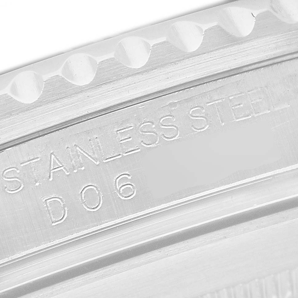 The image shows an extreme close-up of the engraved inner bezel of a Rolex Submariner 16610 Men's Stainless Steel Black Dial, reading "STAINLESS STEEL."