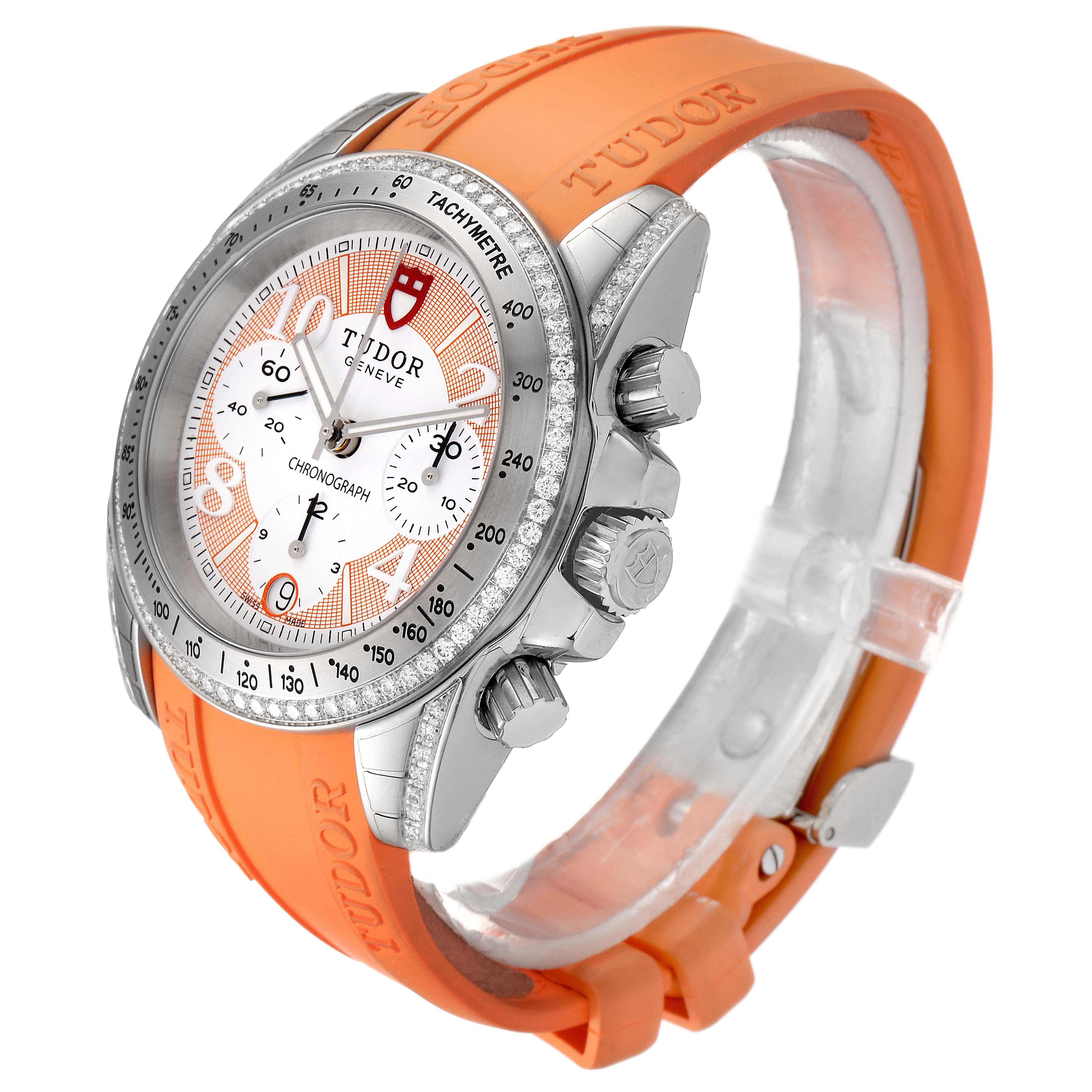 The image shows a Tudor Grantour 20310 Men's Stainless Steel White Dial 20310 Men's Stainless Steel White Dial watch with a silver bezel, white dial, chronograph subdials, and an orange rubber strap.