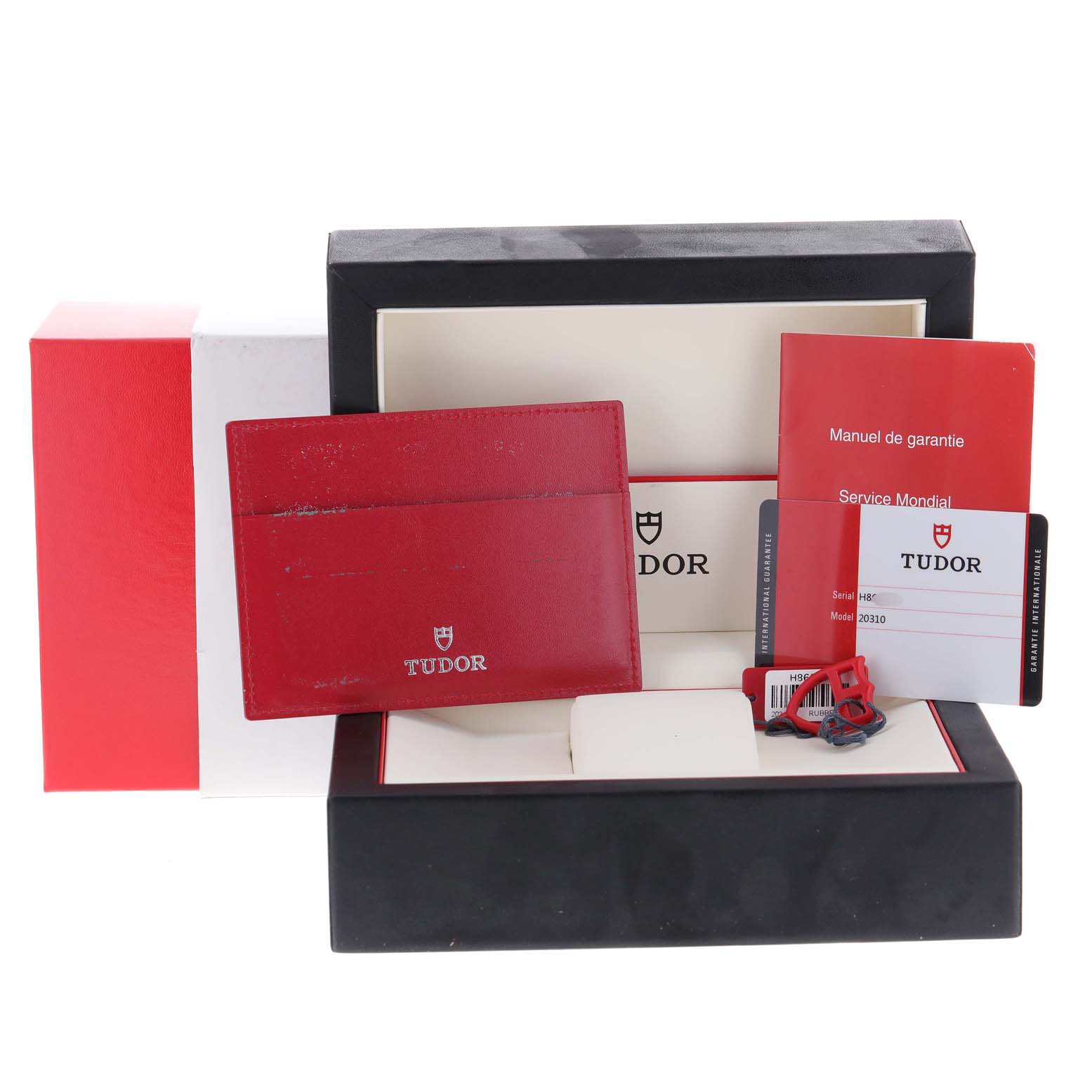 The image shows packaging and accessories of the Tudor Grantour 20310 Men's Stainless Steel White Dial 20310 Men's Stainless Steel White Dial model, including a box, manual, cardholder, and tags.