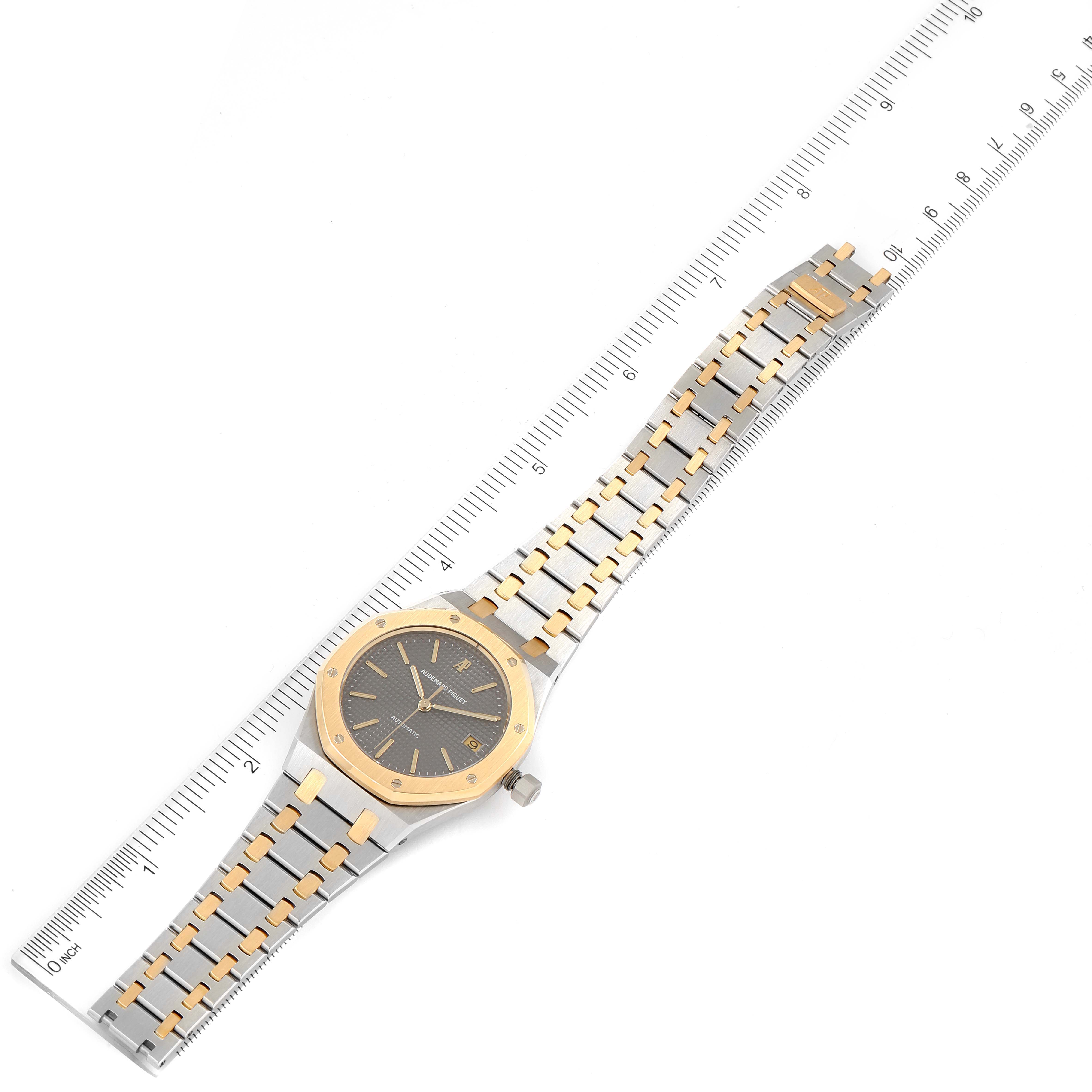 The Audemars Piguet Royal Oak 14700SA.00.0789SA.01.B Men's Steel and Gold (two tone) Grey Dial 14700SA.00.0789SA.01.B Men's Steel and Gold (two tone) Grey Dial watch is displayed from a top-down angle, showing the face and entire bracelet against a measuring ruler.