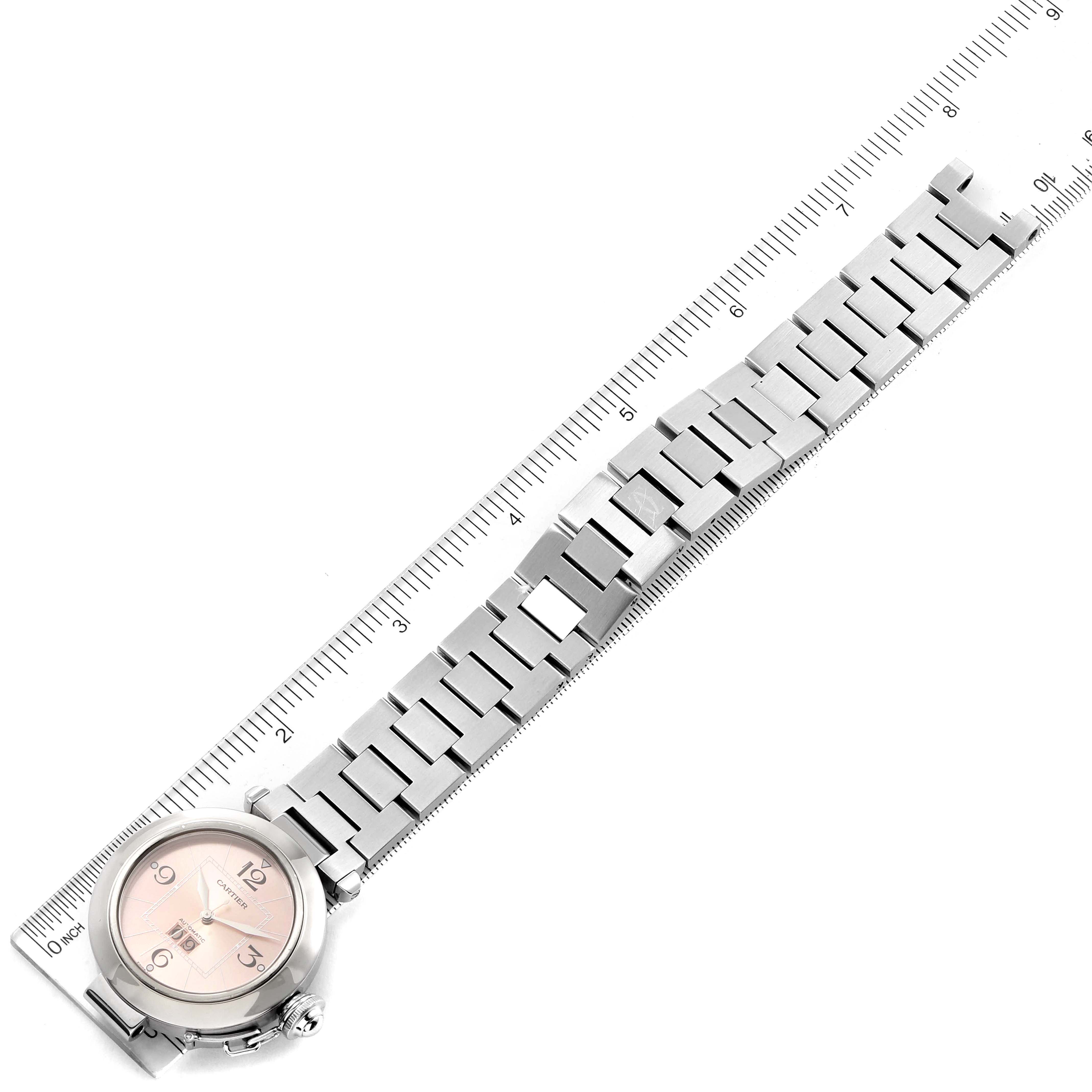 The image shows a Cartier Pasha W31058M7 Women's Stainless Steel Pink Dial W31058M7 Women's Stainless Steel Pink Dial model watch laid flat against a ruler, highlighting the watch face and metal bracelet.