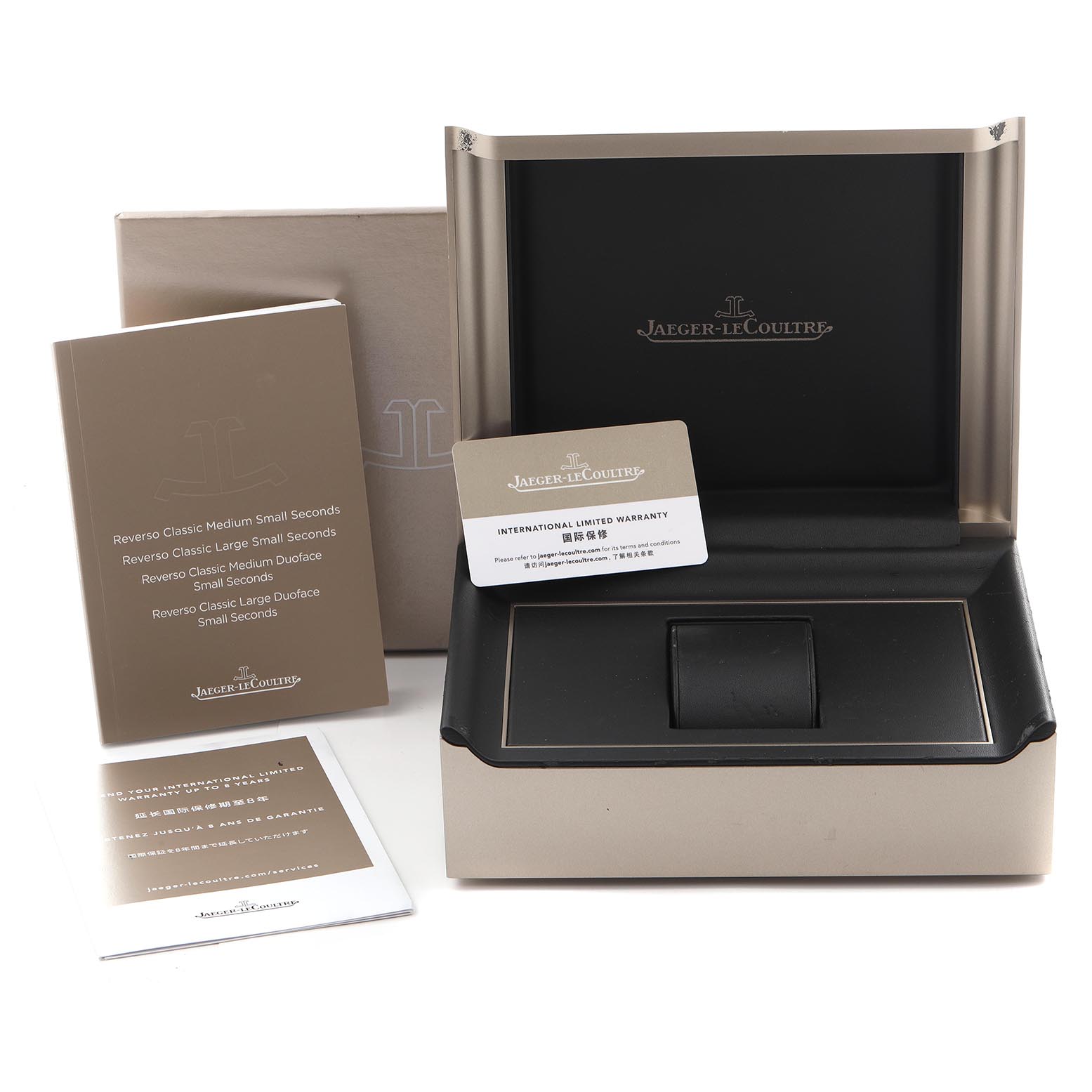 The image shows the packaging, manuals, and warranty card of a Jaeger-LeCoultre Reverso watch, without the watch itself.