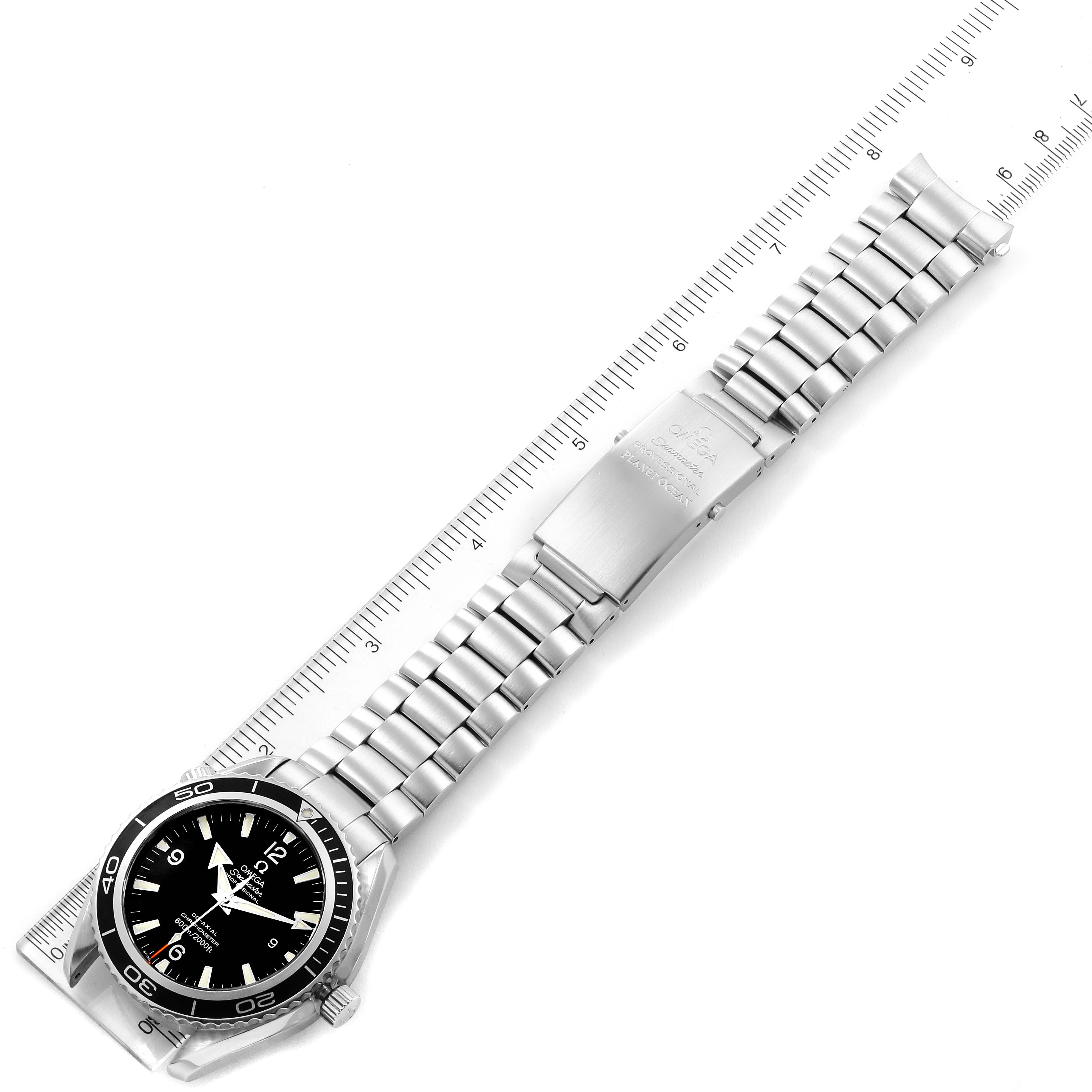 The image shows an Omega Planet Ocean 2200.50.00 Men
s Stainless Steel Black Dial 2200.50.00 Men
s Stainless Steel Black Dial watch lying flat, with its silver metal bracelet fully extended and a ruler next to it.