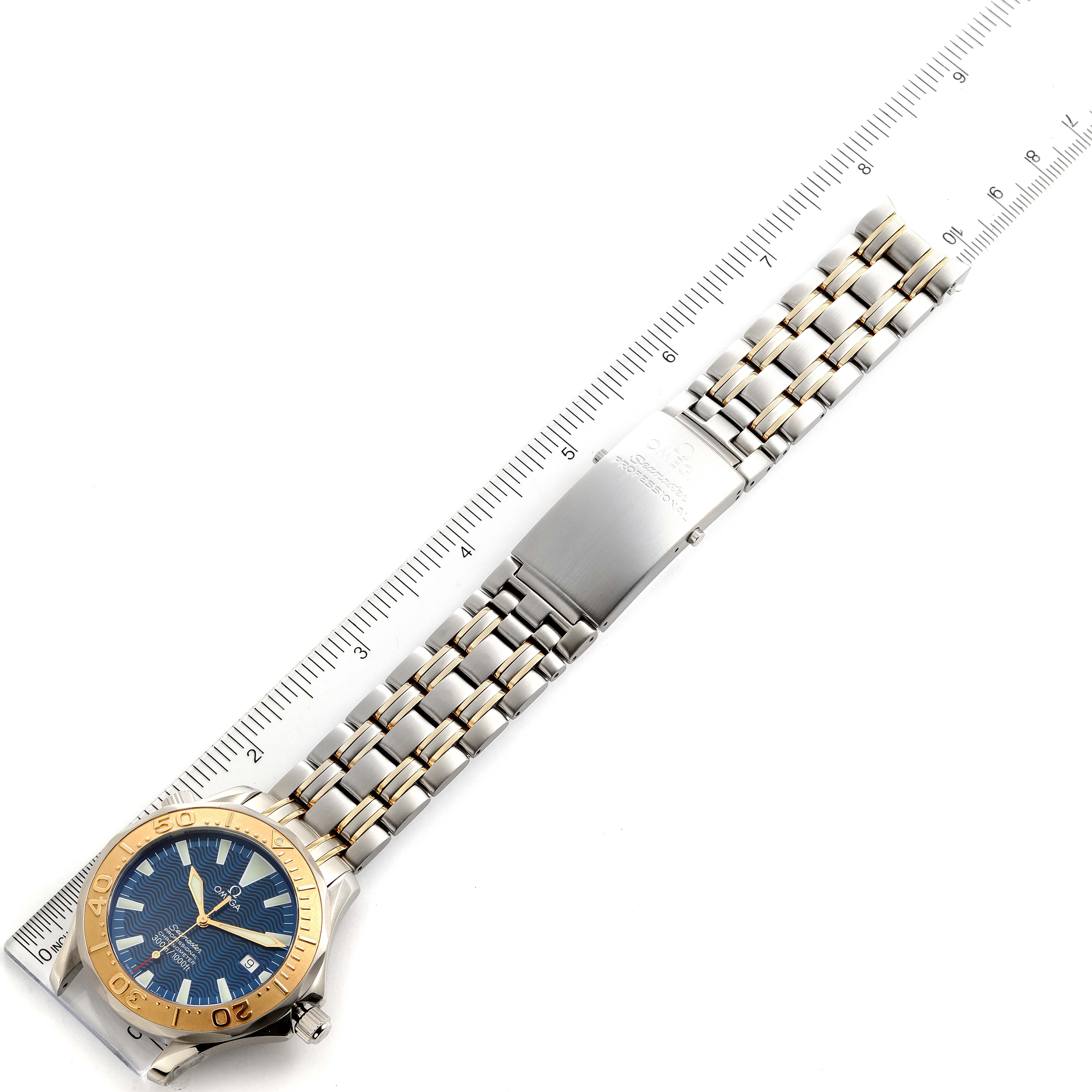 The Omega Seamaster 2455.80.00 Men's Steel and Gold (two tone) Blue Dial 2455.80.00 Men's Steel and Gold (two tone) Blue Dial watch is shown at an angle displaying the face, bezel, and bracelet against a measuring ruler.