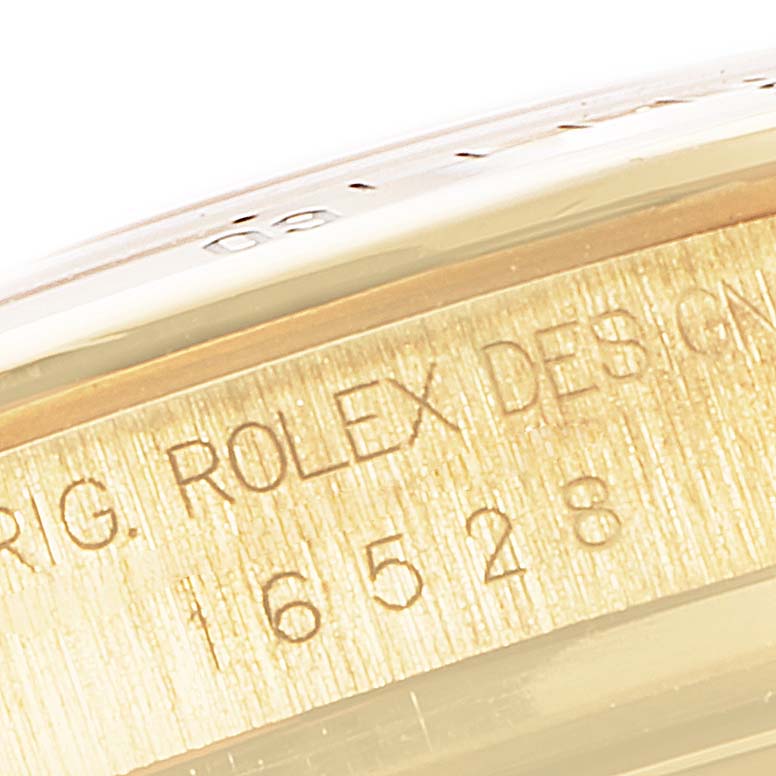 This image shows a close-up of the inner bezel of a Rolex Daytona 16528 Men's Yellow Gold Black Dial 16528 Men's Yellow Gold Black Dial watch, displaying model number and part of the serial engraving.