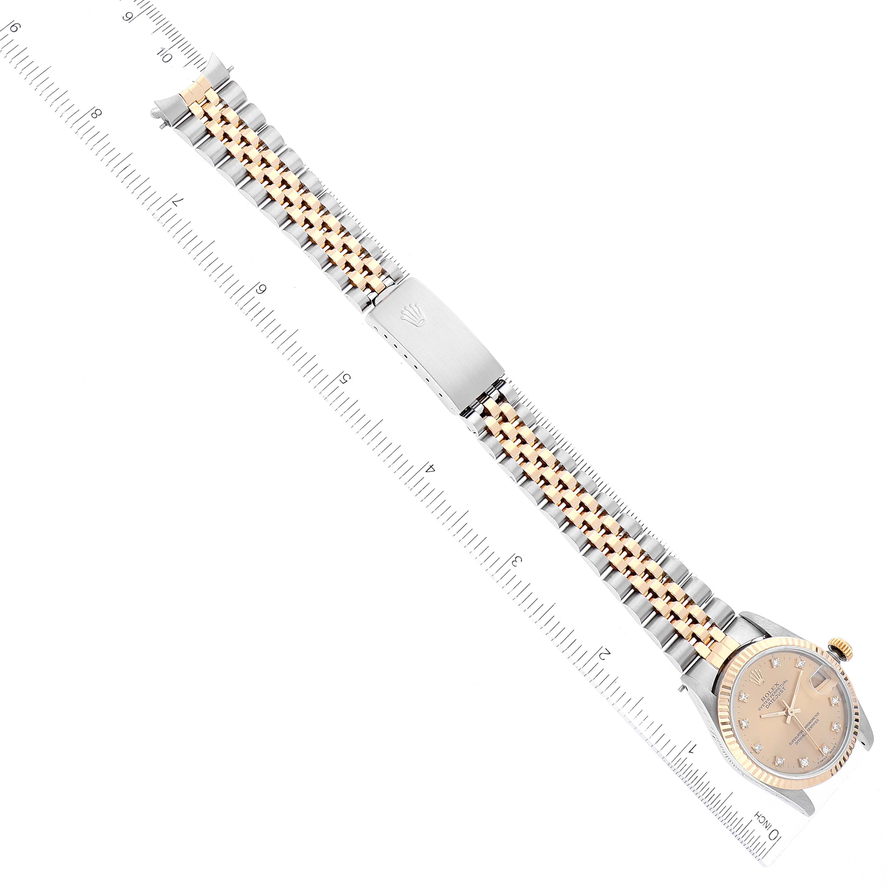 This image shows a full frontal view of a Rolex Mid-Size 68273 Women
s Steel and Gold (two tone) Champagne Dial 68273 Women
s Steel and Gold (two tone) Champagne Dial watch with a gold and silver bracelet against a ruler for scale.
