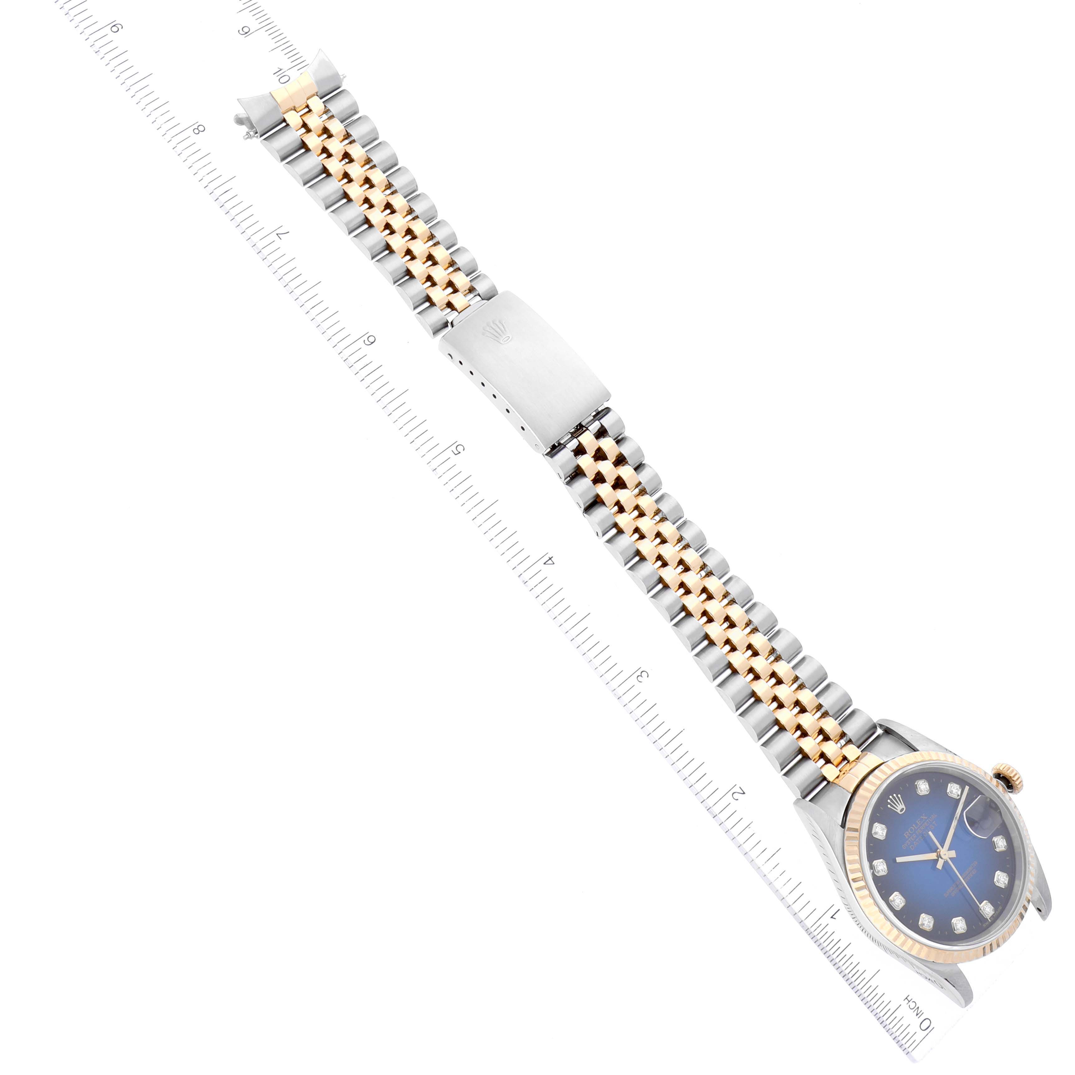 The image shows a Rolex Datejust 16233 Men's Steel and Gold (two tone) Blue Dial 16233 Men's Steel and Gold (two tone) Blue Dial watch at an oblique angle, featuring its band, clasp, and face with a ruler for scale.