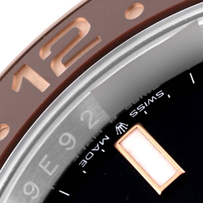 The image shows a close-up of the bezel and part of the dial of a Rolex GMT-Master 126711CHNR Men's Steel and Gold (two tone) Black Dial 126711CHNR Men's Steel and Gold (two tone) Black Dial watch, featuring the number 12 and "Swiss Made" text.