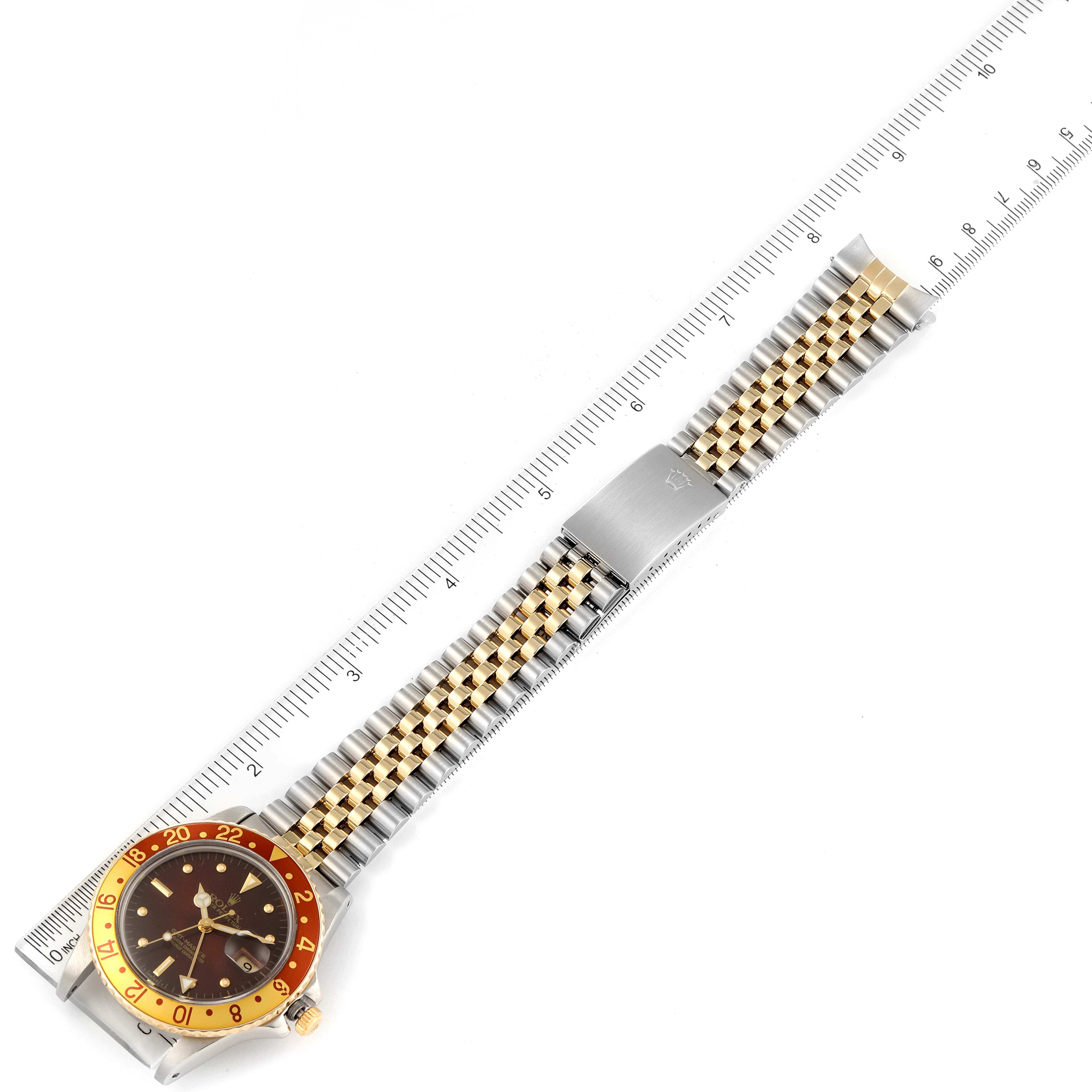 The image shows a top-down view of a Rolex Vintage Collection 16753 Men's Steel and Gold (two tone) Brown Dial 16753 Men's Steel and Gold (two tone) Brown Dial watch with its gold-tone and silver bracelet, alongside a ruler for scale.