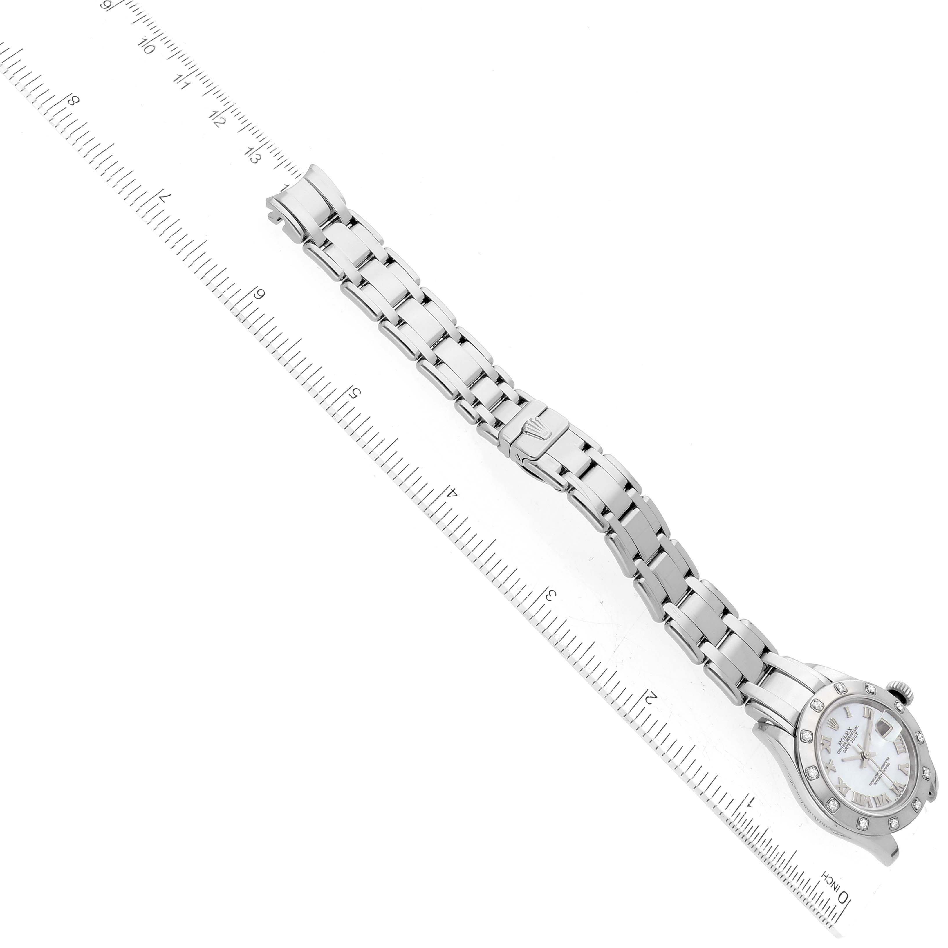 The image shows an overhead view of a Rolex Pearlmaster 80319 Women's White Gold Mother of Pearl Dial 80319 Women's White Gold Mother of Pearl Dial watch, including its face and metal bracelet, aligned next to a ruler.