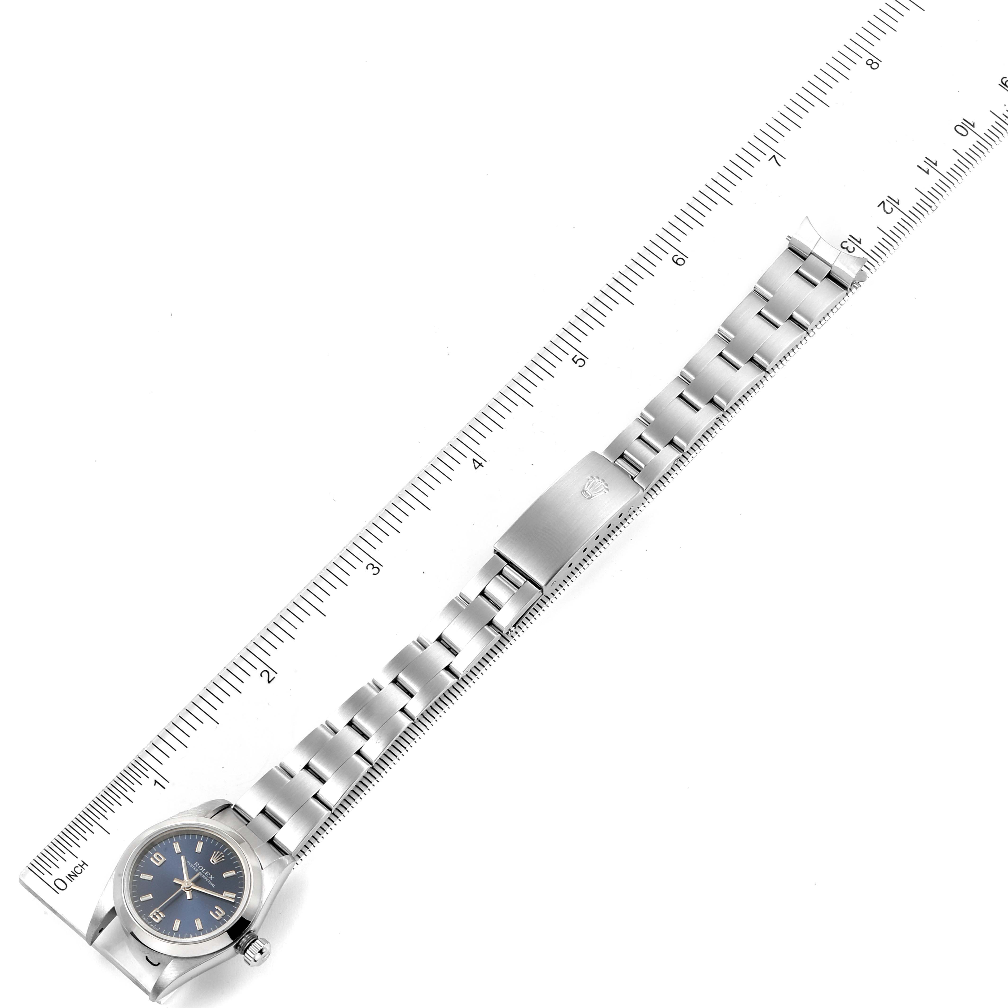 The Rolex Oyster Perpetual 76080 Women
s Stainless Steel Blue Dial 76080 Women
s Stainless Steel Blue Dial watch is shown from a top-down angle, with the bracelet extended alongside a ruler for measurement.