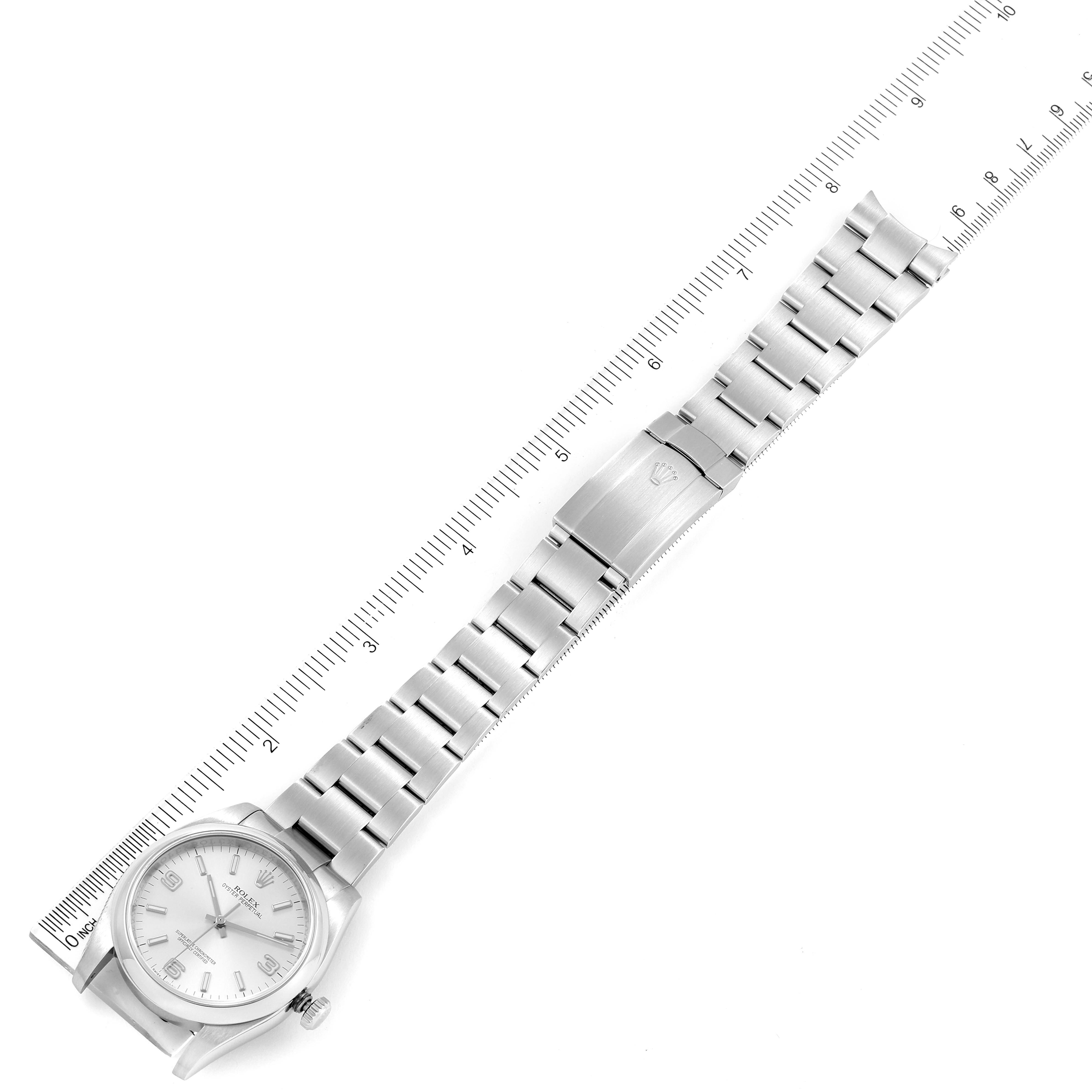The image shows a Rolex Oyster Perpetual 116000 Men's Stainless Steel Silver Dial 116000 Men's Stainless Steel Silver Dial watch laid flat alongside a ruler, displaying its face, bracelet, and clasp.