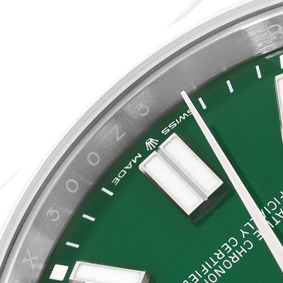This close-up image of a Rolex Oyster Perpetual 124300 Men's Stainless Steel Green Dial 124300 Men's Stainless Steel Green Dial watch shows part of the green dial and edge of the bezel with hour markers.