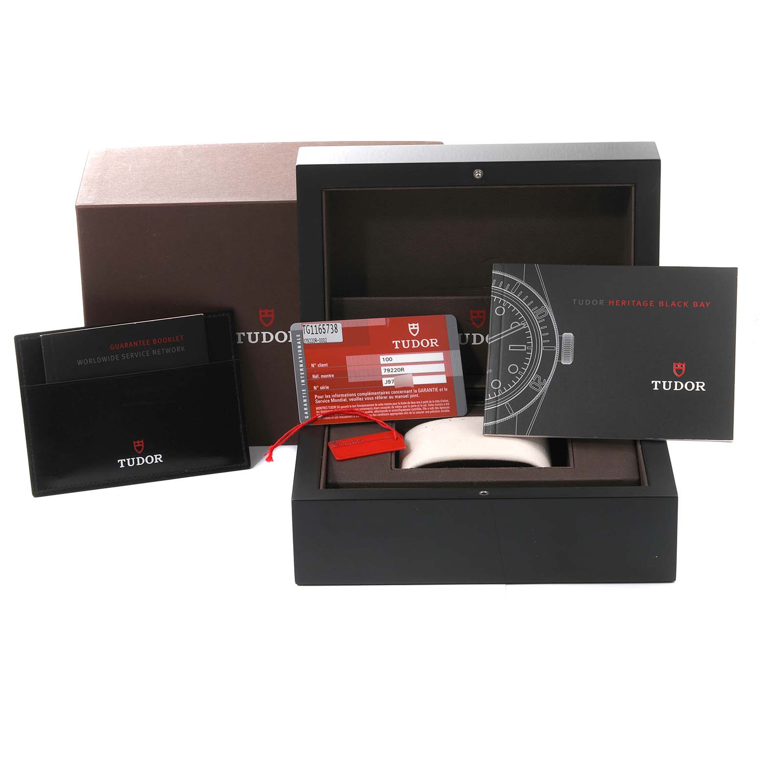 The image shows the open packaging box, guarantee booklet, warranty card, and manual for the Tudor Heritage Black Bay 79220R Men
s Stainless Steel Black Dial 79220R Men
s Stainless Steel Black Dial watch.
