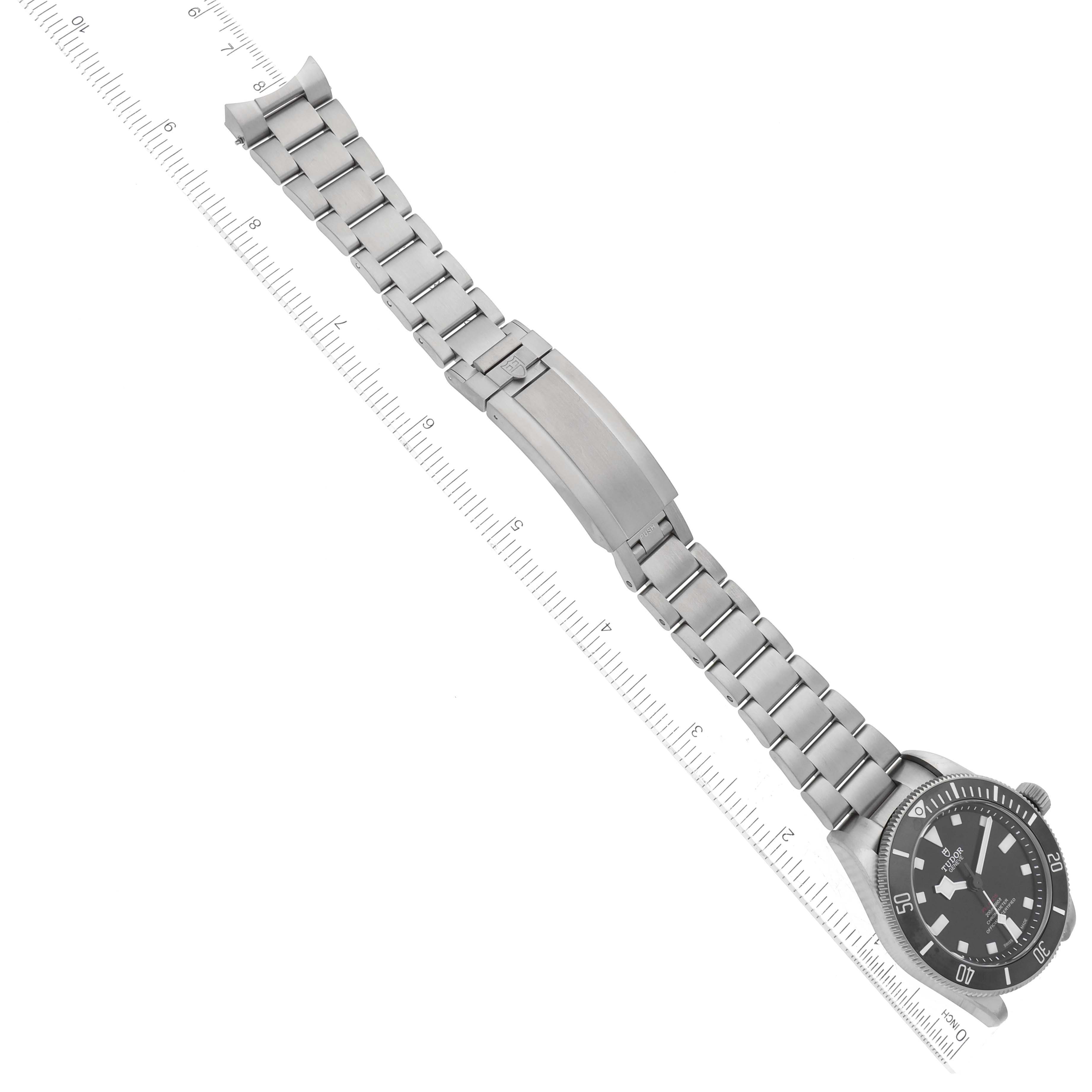 The image shows the Tudor Pelagos 25407N Men
s Titanium Black Dial 25407N Men
s Titanium Black Dial watch displayed diagonally, including the watch face, bracelet, and clasp, alongside a ruler for scale.