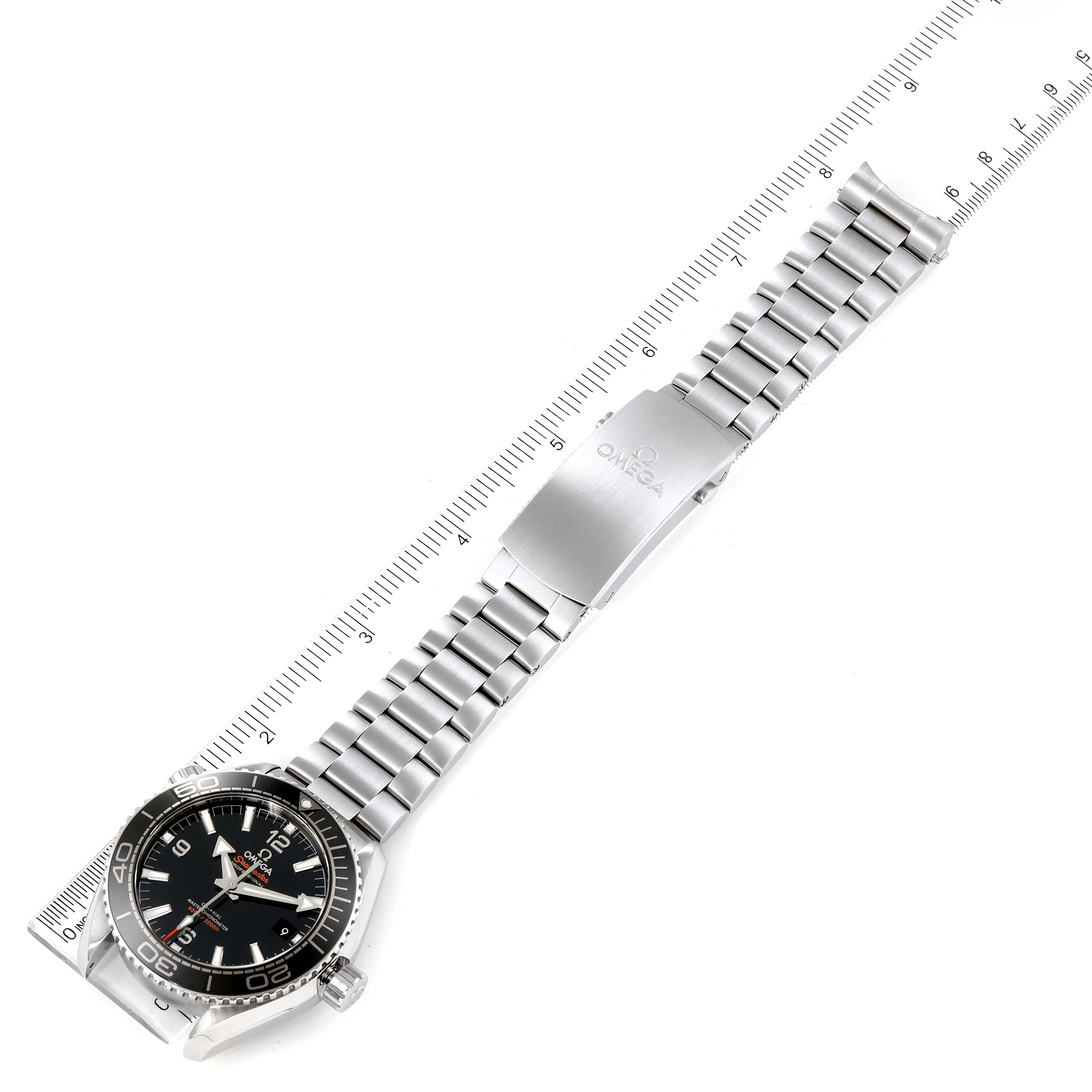 The Omega Planet Ocean 215.30.44.21.01.001 Men's Stainless Steel Black Dial 215.30.44.21.01.001 Men's Stainless Steel Black Dial watch is shown laid flat, highlighting the face, bezel, and stainless steel bracelet with a ruler for scale.