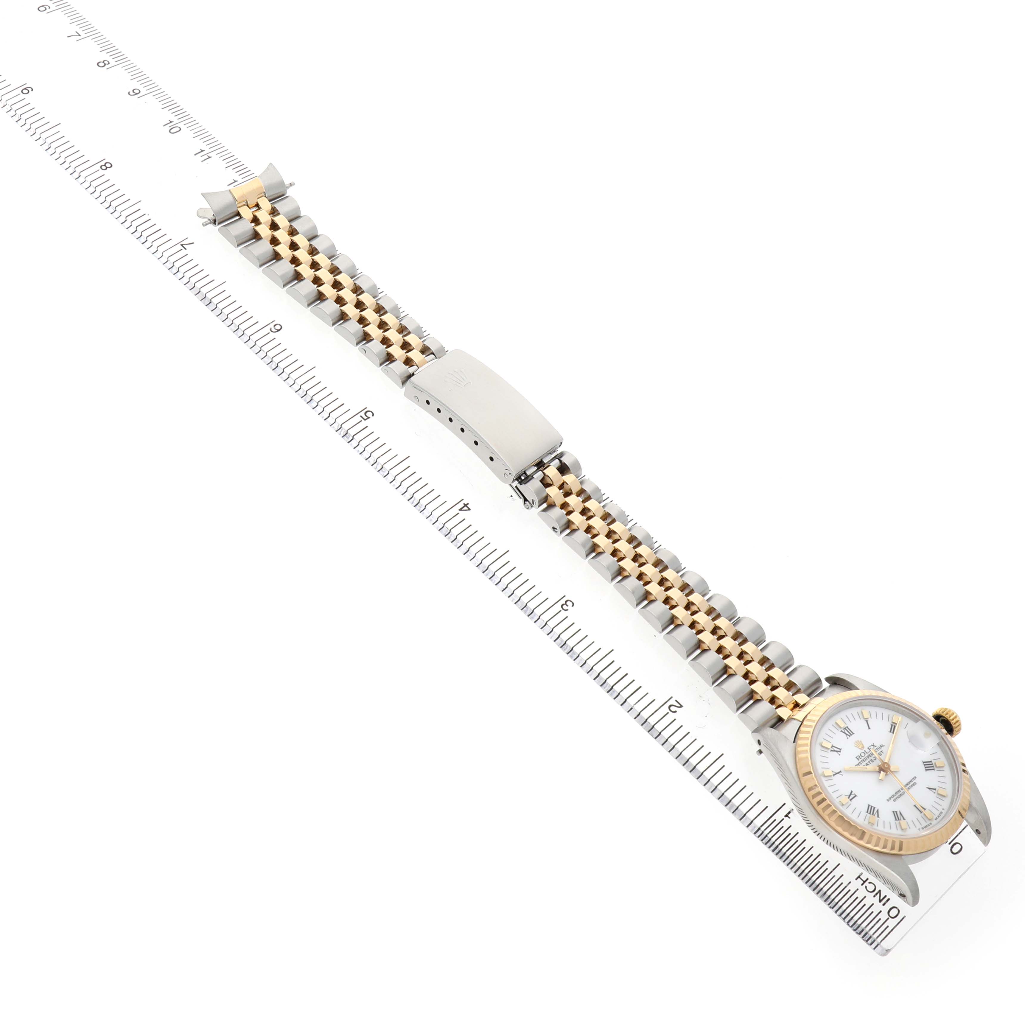 The Rolex Mid-Size 68273 Women's Steel and Gold (two tone) White Dial watch is shown from an angled top view, displaying the full bracelet, clasp, and the face with a ruler for scale.