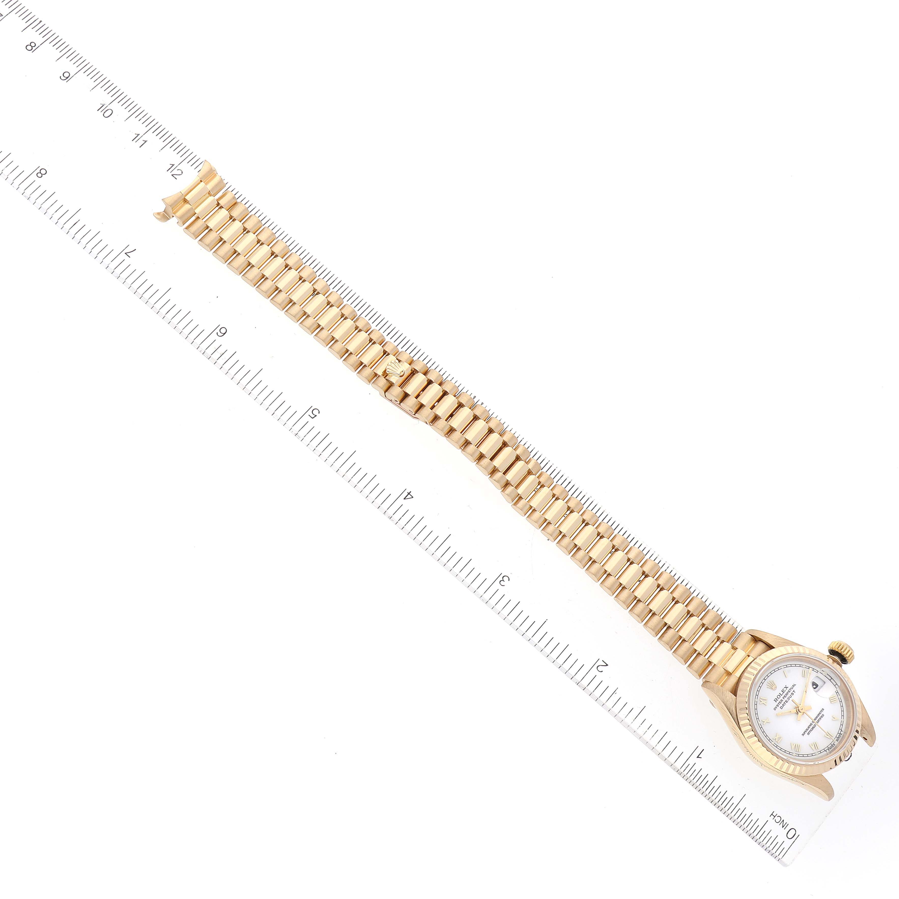 The image shows the side view of a Rolex President 69178 Women's Yellow Gold White Dial 69178 Women's Yellow Gold White Dial model watch, focusing on its gold bracelet and dial, with a ruler for scale.