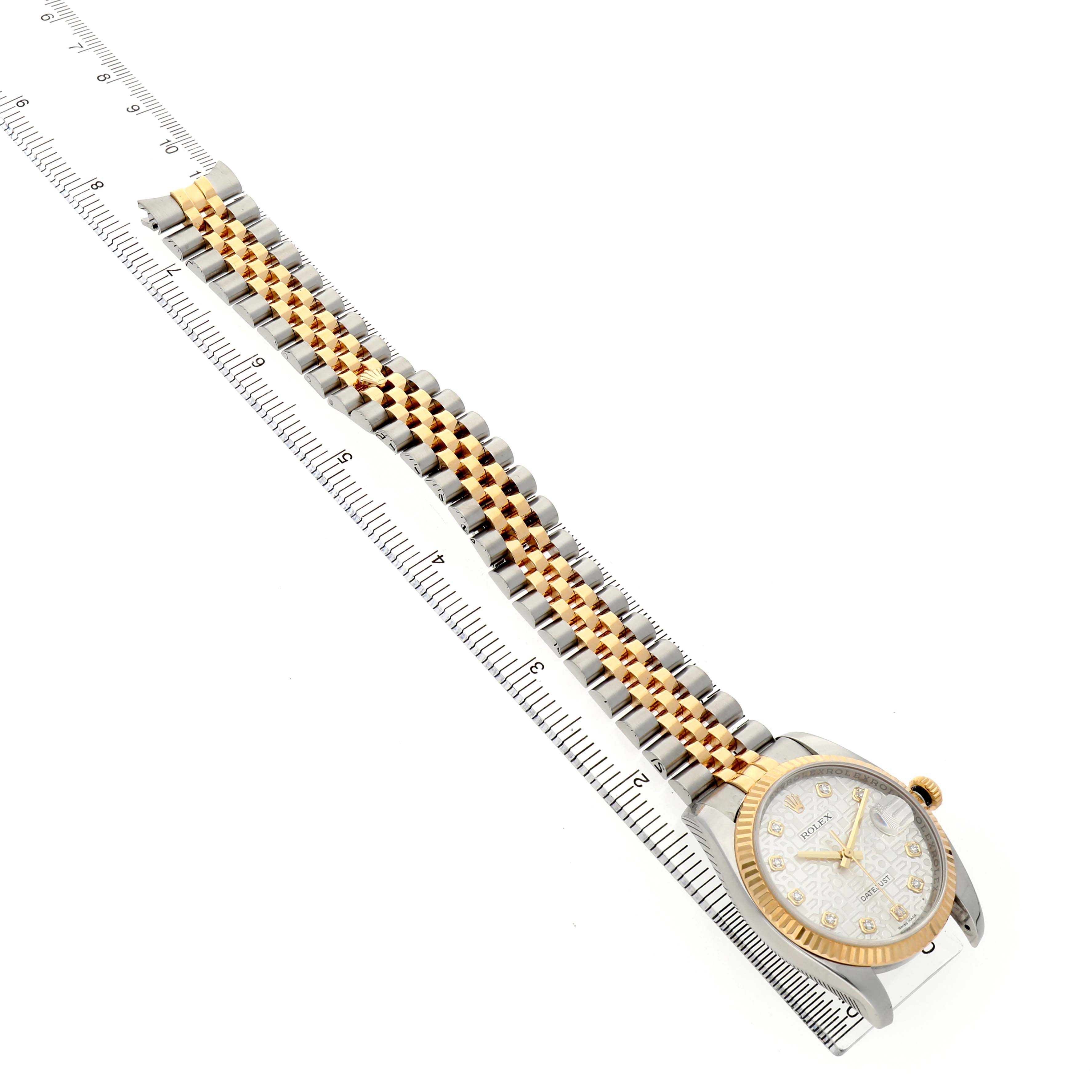 The image shows a side view of the Rolex Datejust 116233 Men's Steel and Gold (two tone) Silver Dial watch, highlighting its jubilee bracelet, bezel, and dial against a ruler.
