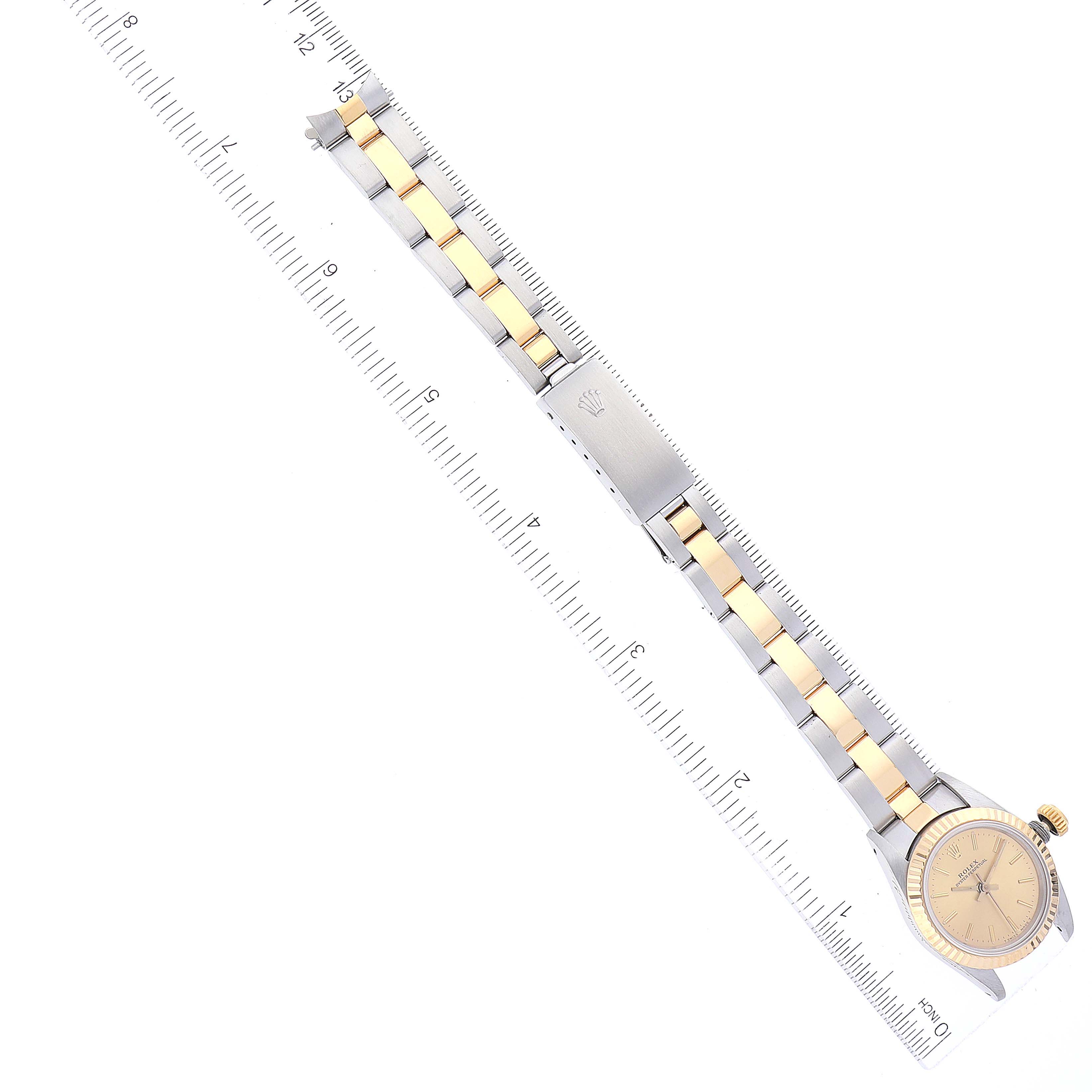This image features a top-down view of a Rolex Oyster Perpetual 67193 Women's Steel and Gold (two tone) Champagne Dial 67193 Women's Steel and Gold (two tone) Champagne Dial watch, showcasing the band and watch face along a measuring ruler.