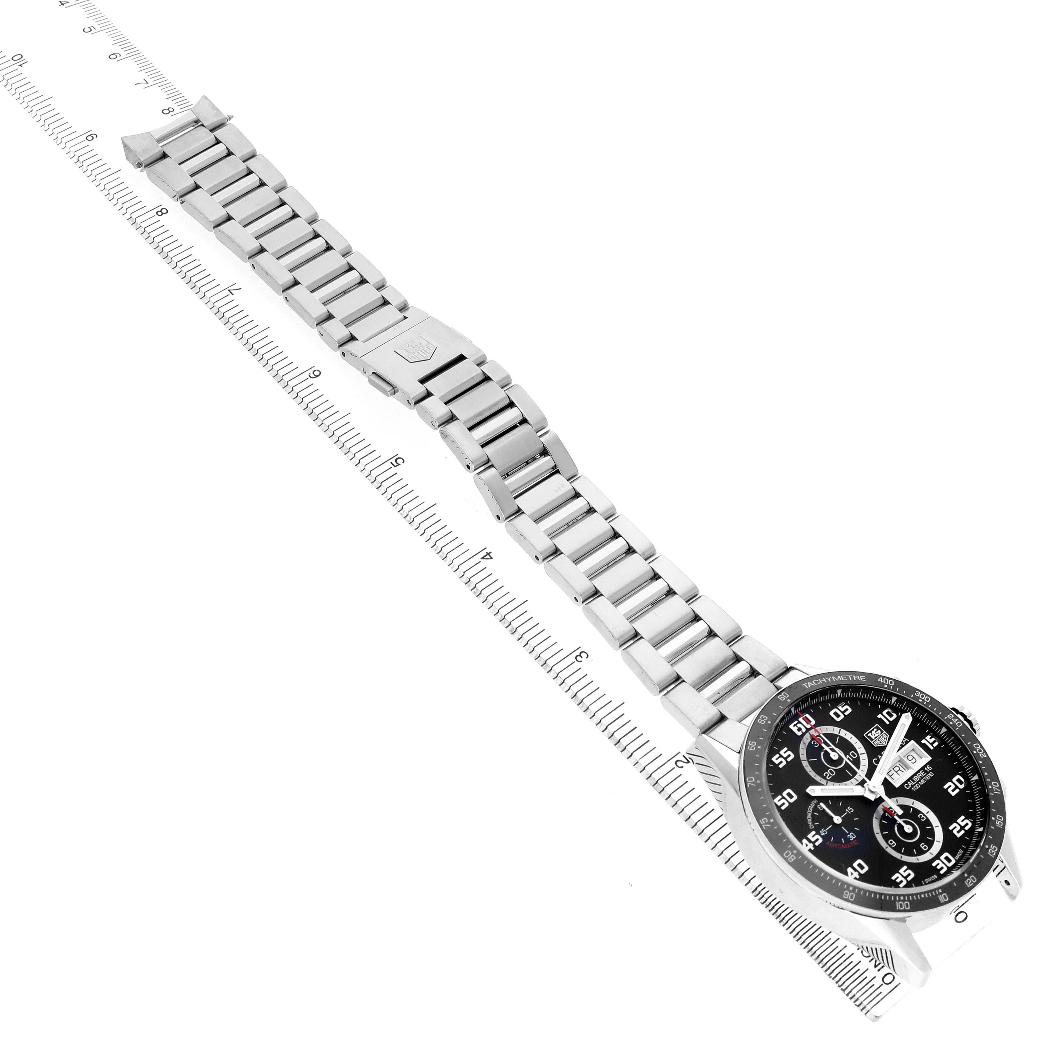 The image shows the Tag Heuer Carrera CV2A1R Men's Stainless Steel Black Dial watch diagonally, highlighting the face and stainless steel bracelet above a ruler.