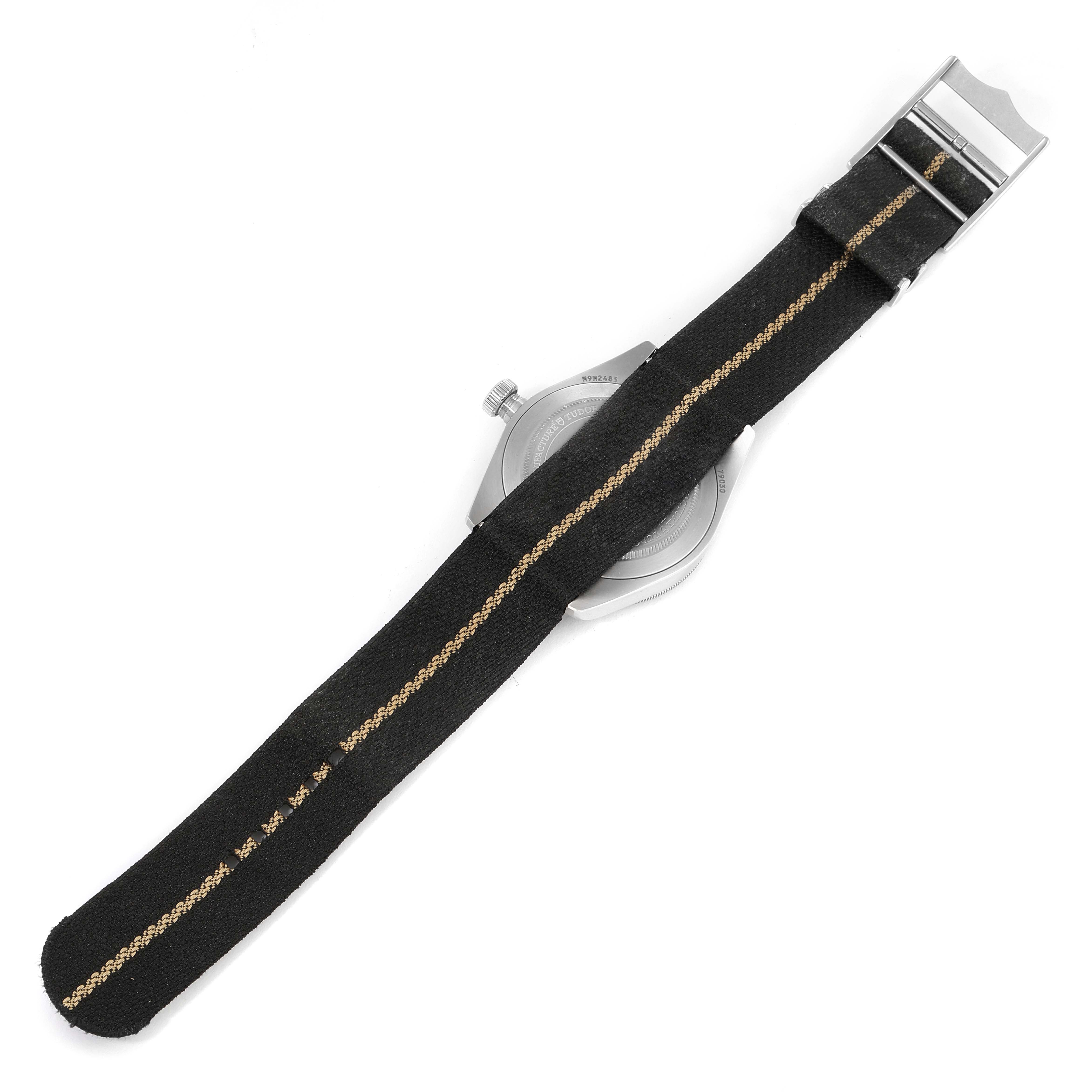 The image shows the back view of the Tudor Heritage Black Bay 79030N Men
s Stainless Steel Black Dial 79030N Men
s Stainless Steel Black Dial watch with a black fabric strap and metal clasp.