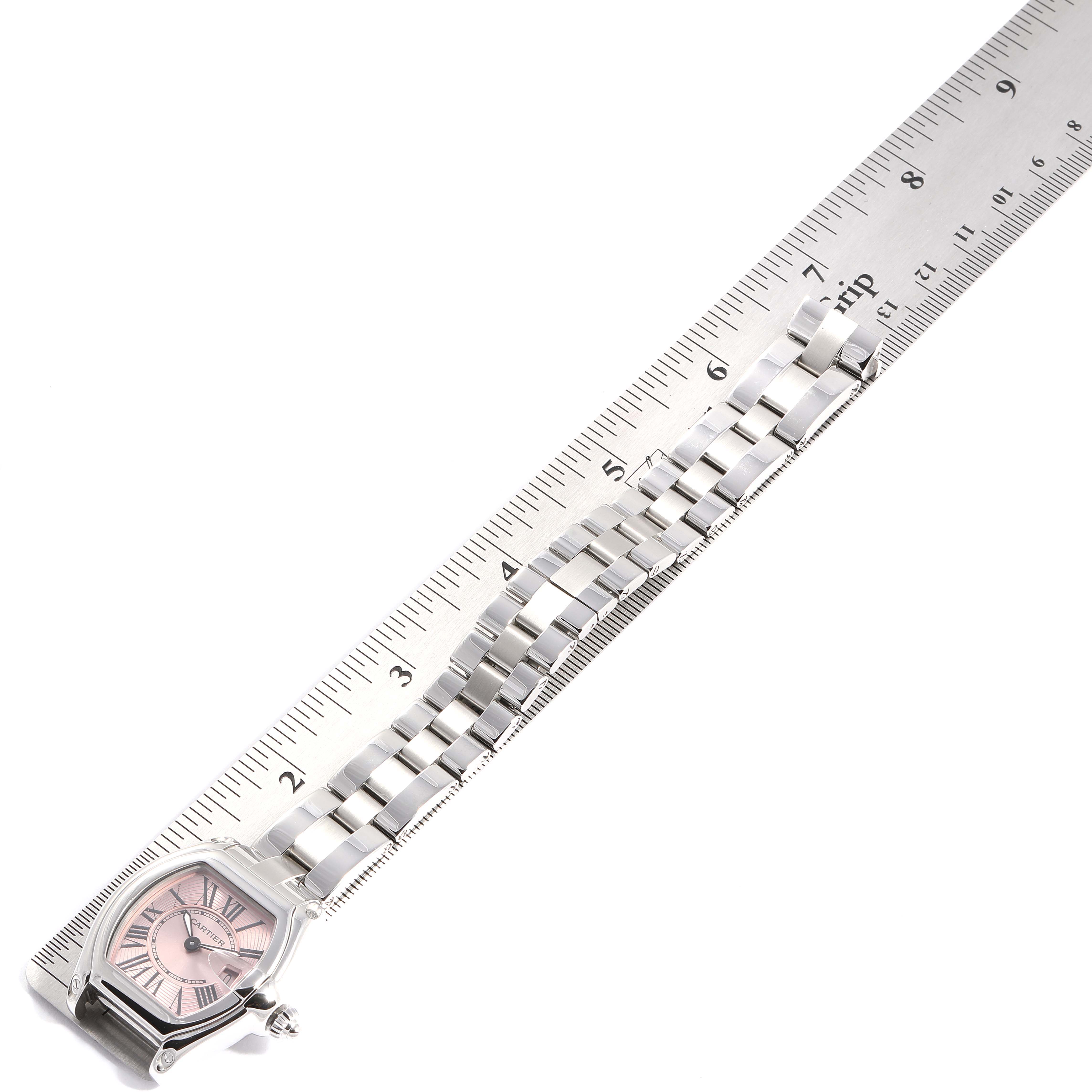 The image shows the Cartier Roadster W62017V3 Women
s Stainless Steel Pink Dial W62017V3 Women
s Stainless Steel Pink Dial watch case and bracelet laid against a ruler, viewed from above.