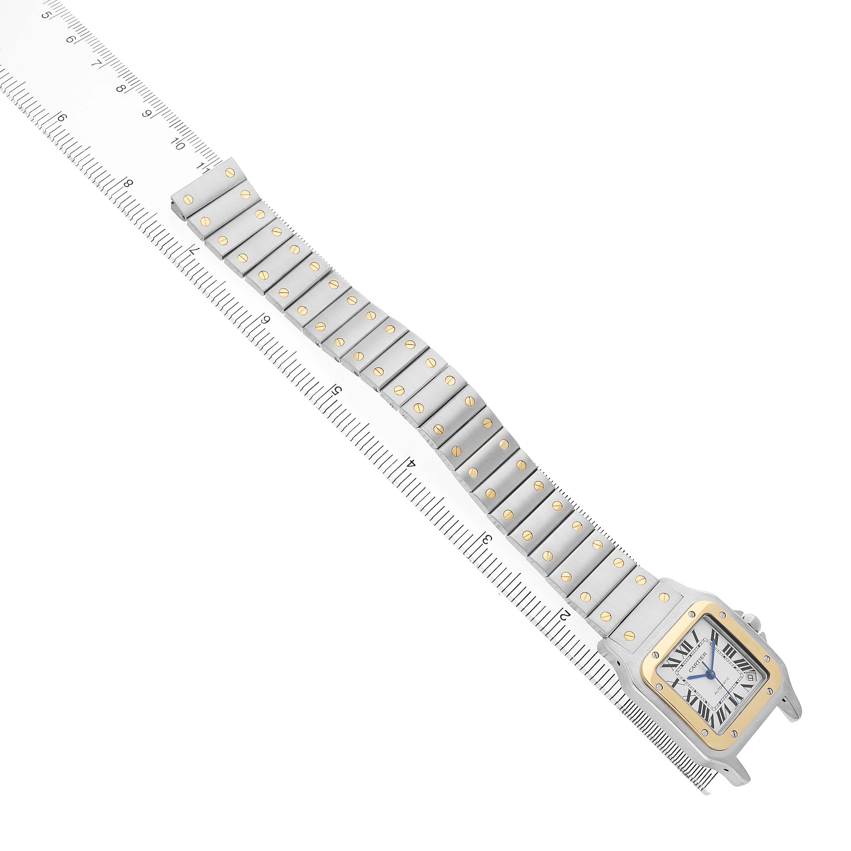 The Cartier Santos W20099C4 Men's Steel and Gold (two tone) Silver Dial watch is shown from a top angle with its full bracelet extended beside a ruler for scale.