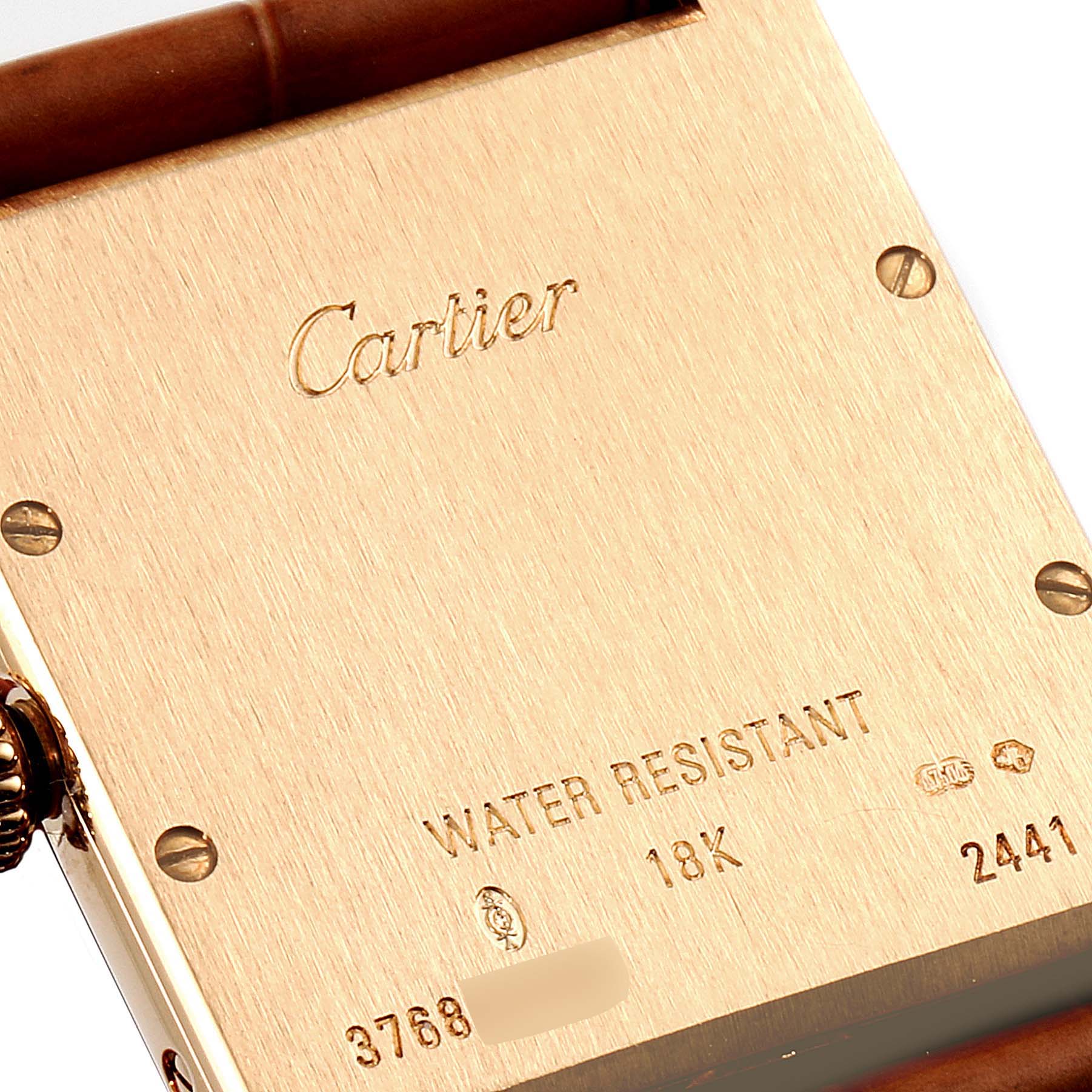 The image shows the back case of a Cartier Tank Louis W1529756 Men's Yellow Gold Silver Dial W1529756 Men's Yellow Gold Silver Dial watch, highlighting its inscriptions and metal screws.
