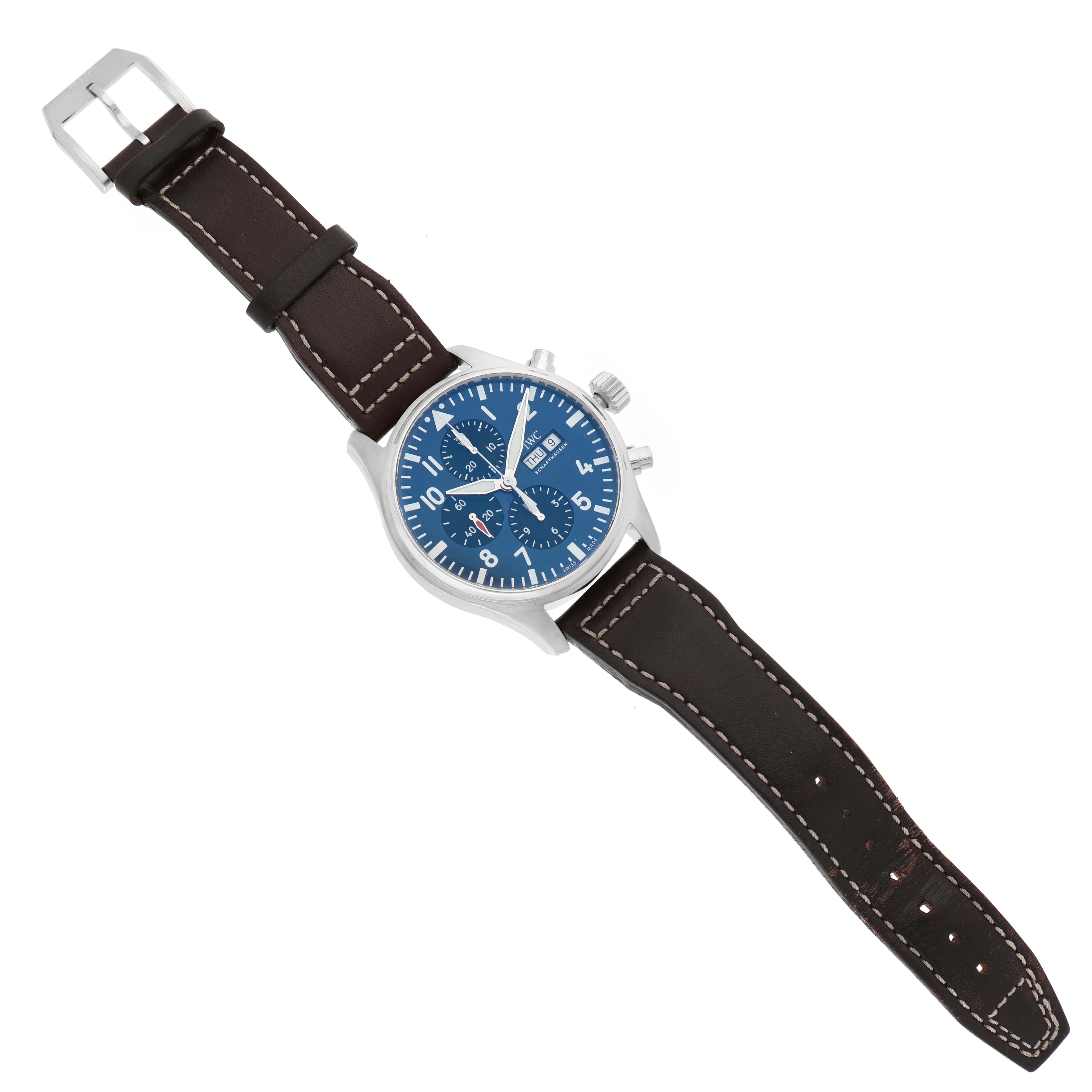 The IWC Pilot IW377714 Men's Stainless Steel Blue Dial watch is shown from a top-down angle, displaying the dial, case, crown, and brown leather strap with stitching.