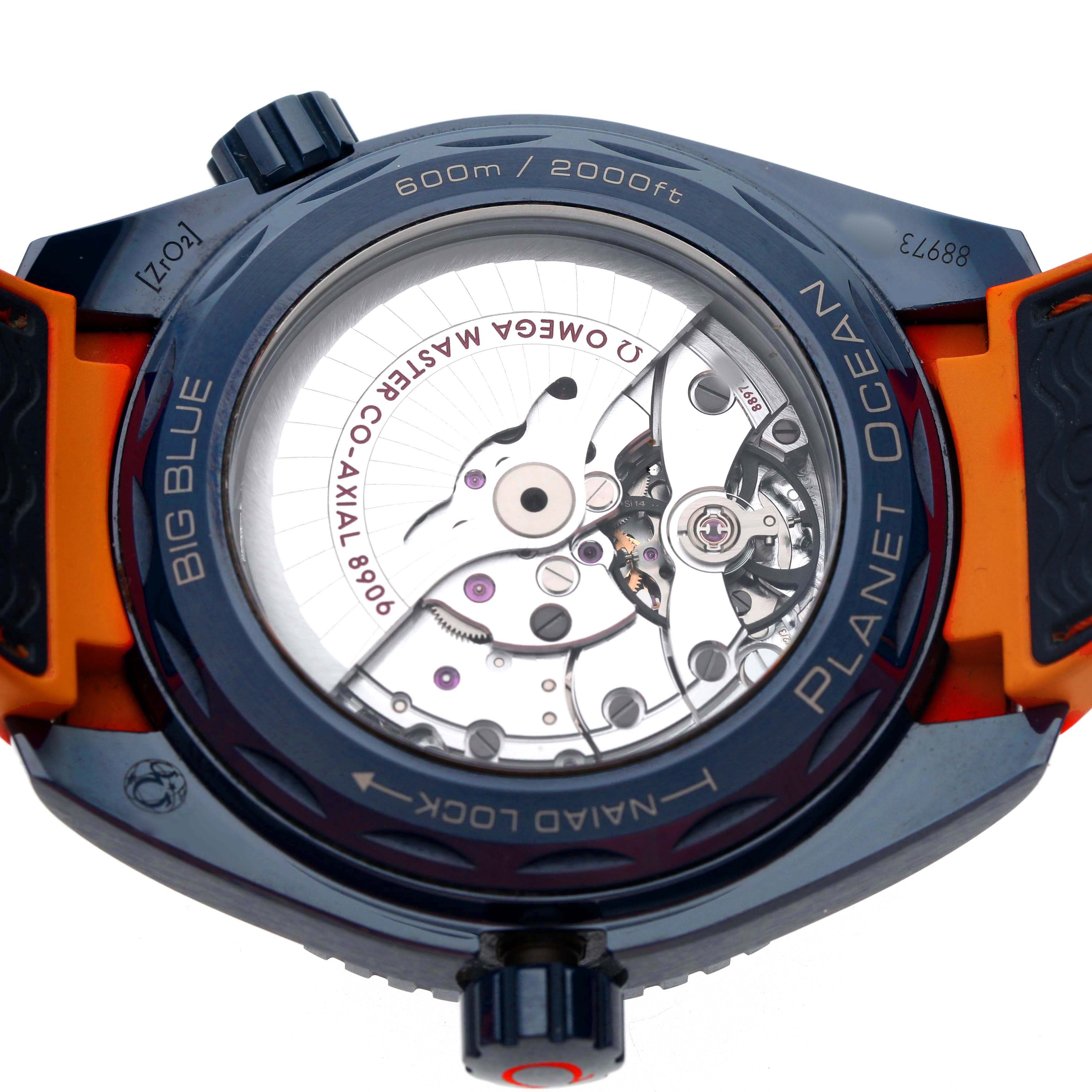 The image shows the back view of an Omega Planet Ocean 215.92.46.22.03.001 Men's Ceramic Blue Dial watch, highlighting its exposed movement and orange strap.