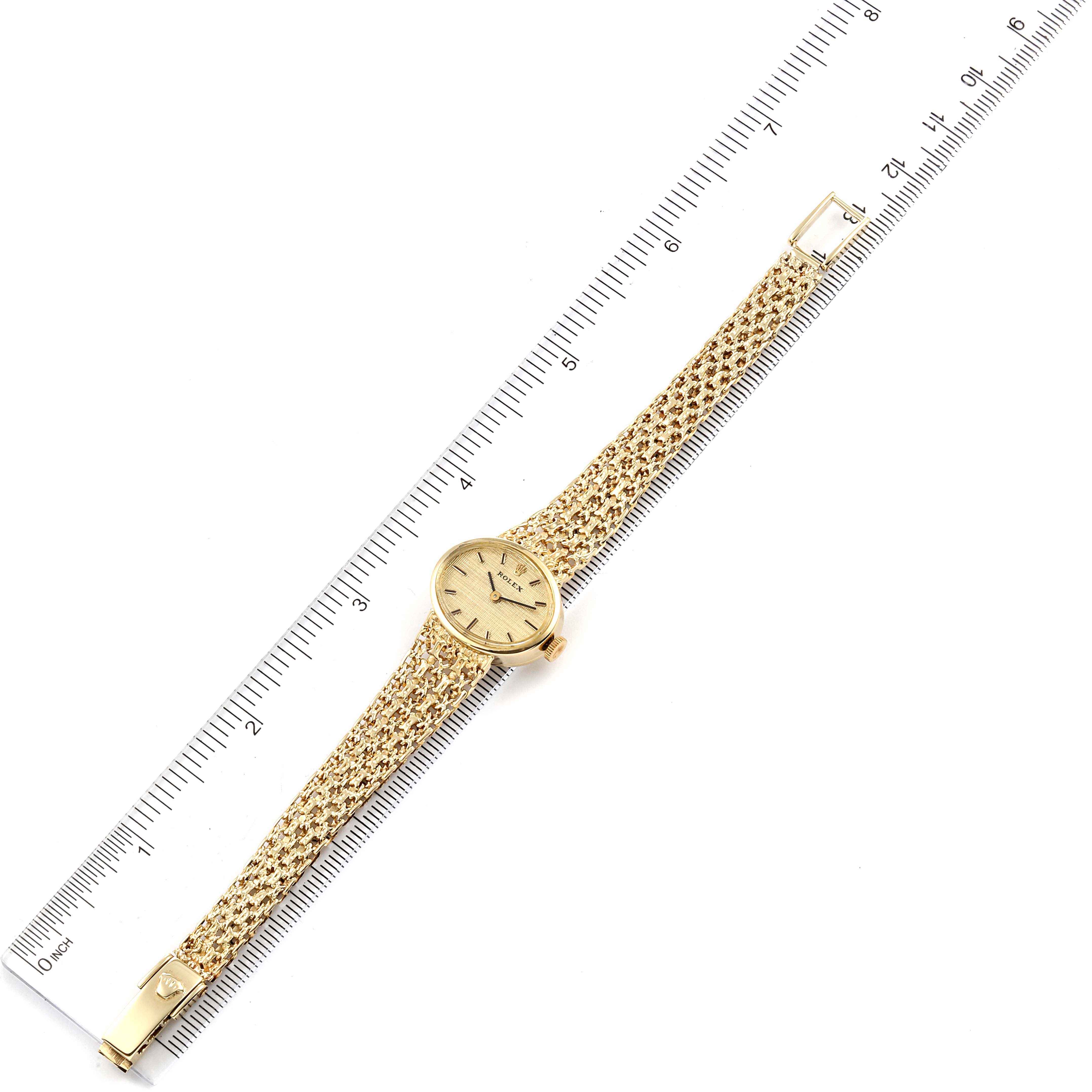 The Rolex Cocktail Women's Yellow Gold Champagne Dial Women's Yellow Gold Champagne Dial model watch is shown from a top-down angle, displaying the face, bracelet, and clasp, placed alongside a ruler for scale.