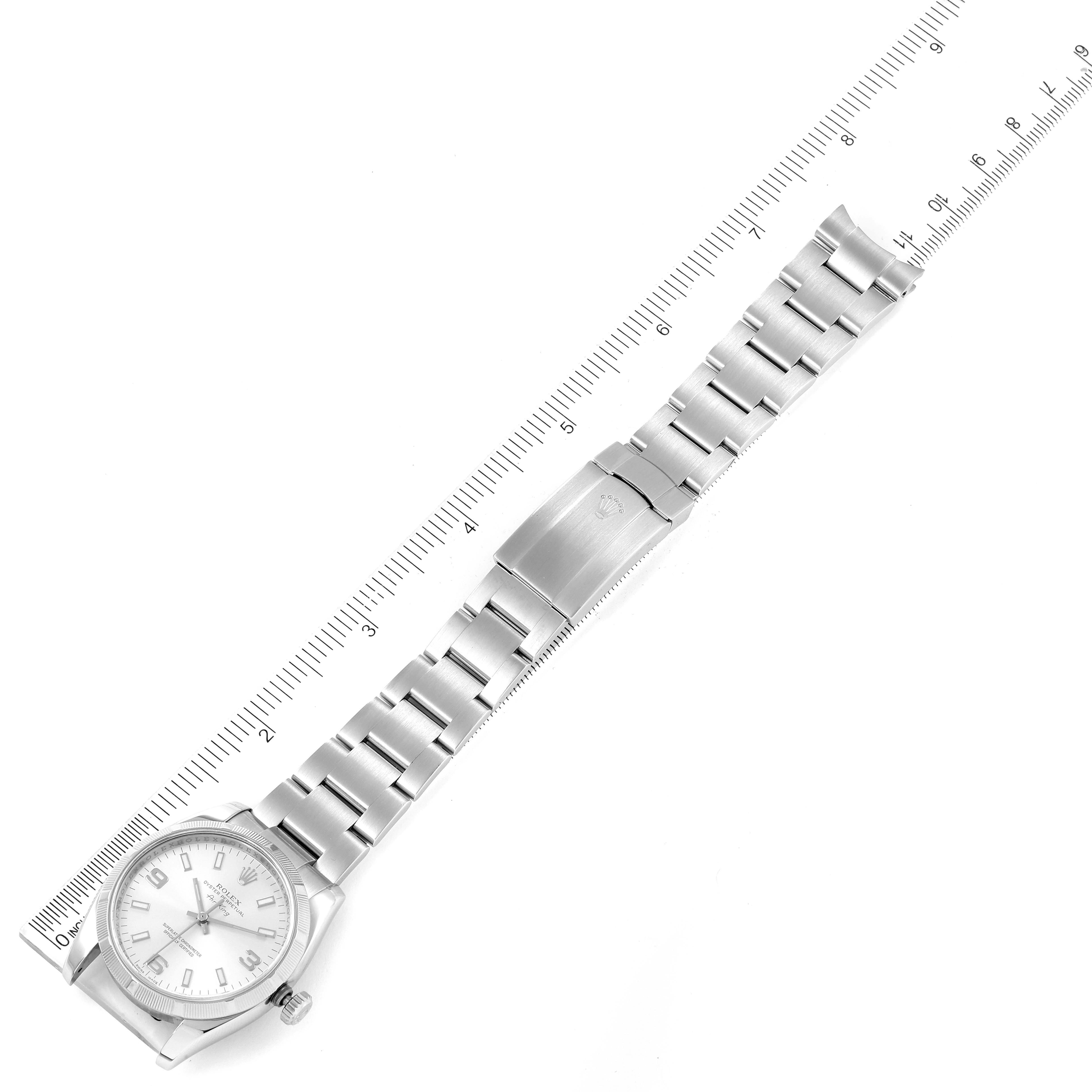 The image shows a full view of the Rolex Air-King 114210 Men's Stainless Steel Silver Dial 114210 Men's Stainless Steel Silver Dial watch laid flat with its bracelet fully extended alongside a ruler for scale.
