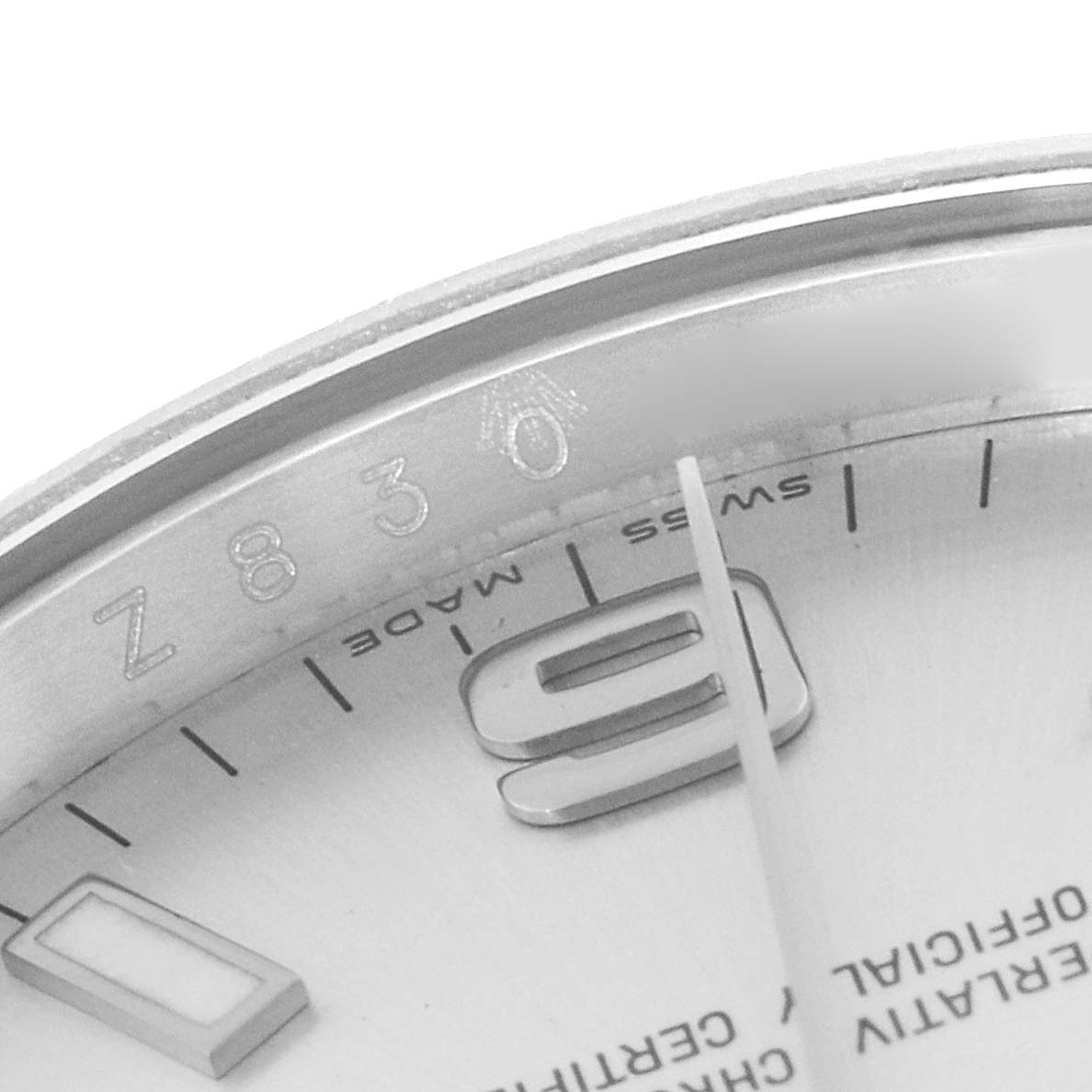 This close-up of a Rolex Air-King 114210 Men's Stainless Steel Silver Dial 114210 Men's Stainless Steel Silver Dial watch shows part of the bezel, dial, and hour markers from a low-oblique angle.