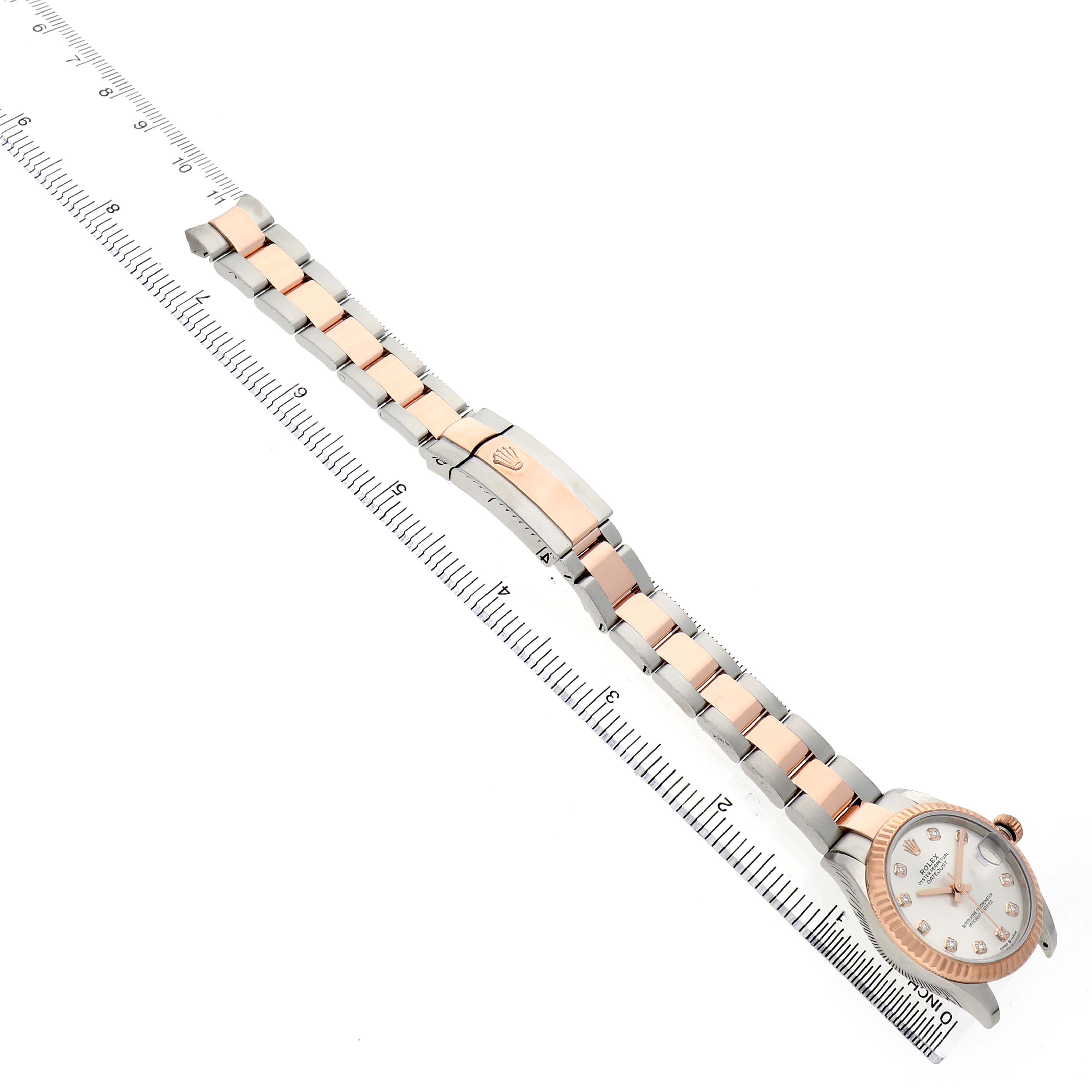 The Rolex Mid-Size 278271 Women's Steel and Gold (two tone) Silver Dial watch is shown from a top-down angle, displaying the face, bracelet, and clasp alongside a ruler.