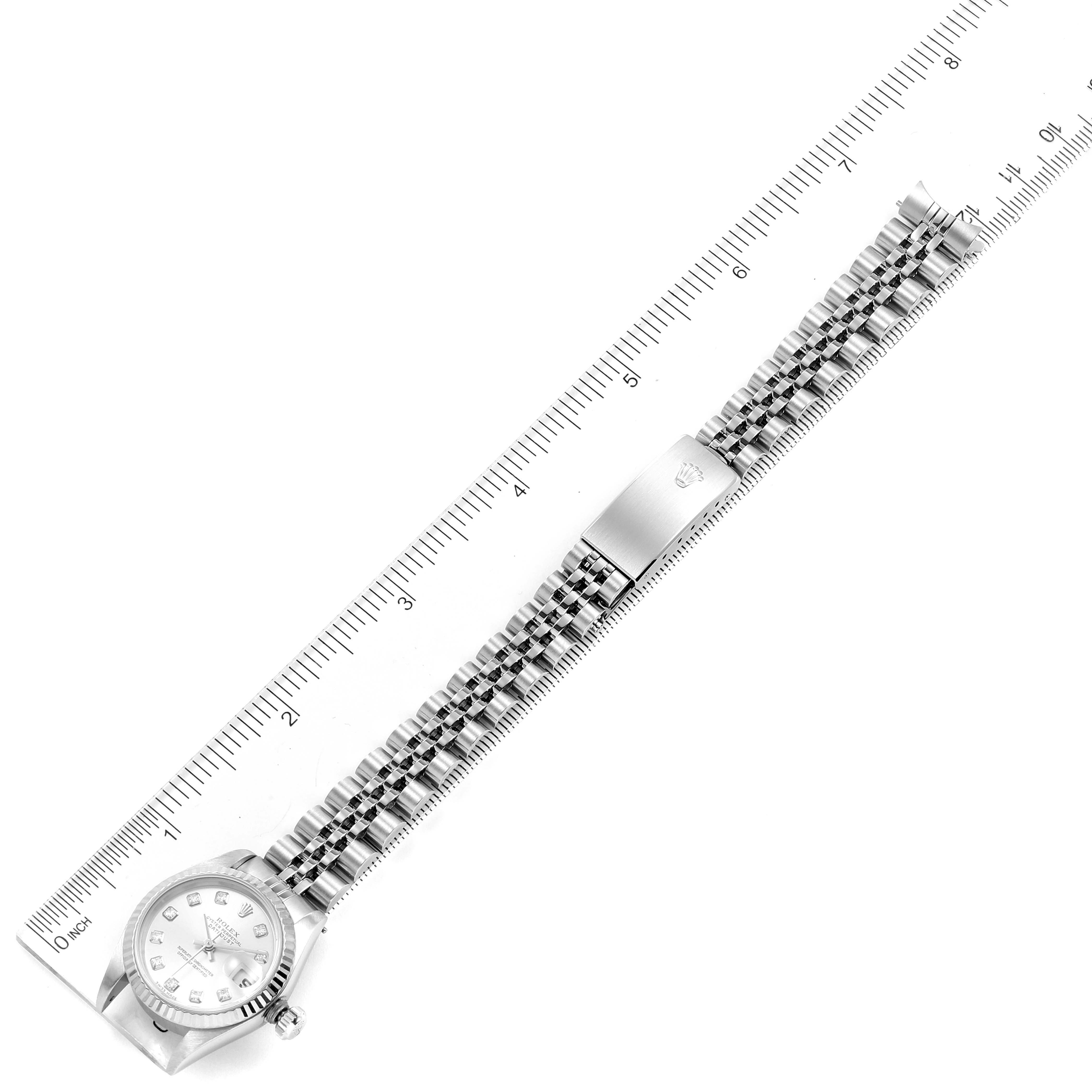 The Rolex Datejust 79174 Women's Stainless Steel Silver Dial 79174 Women's Stainless Steel Silver Dial watch is shown from a top view, highlighting the face, bezel, and full-length bracelet alongside a ruler.