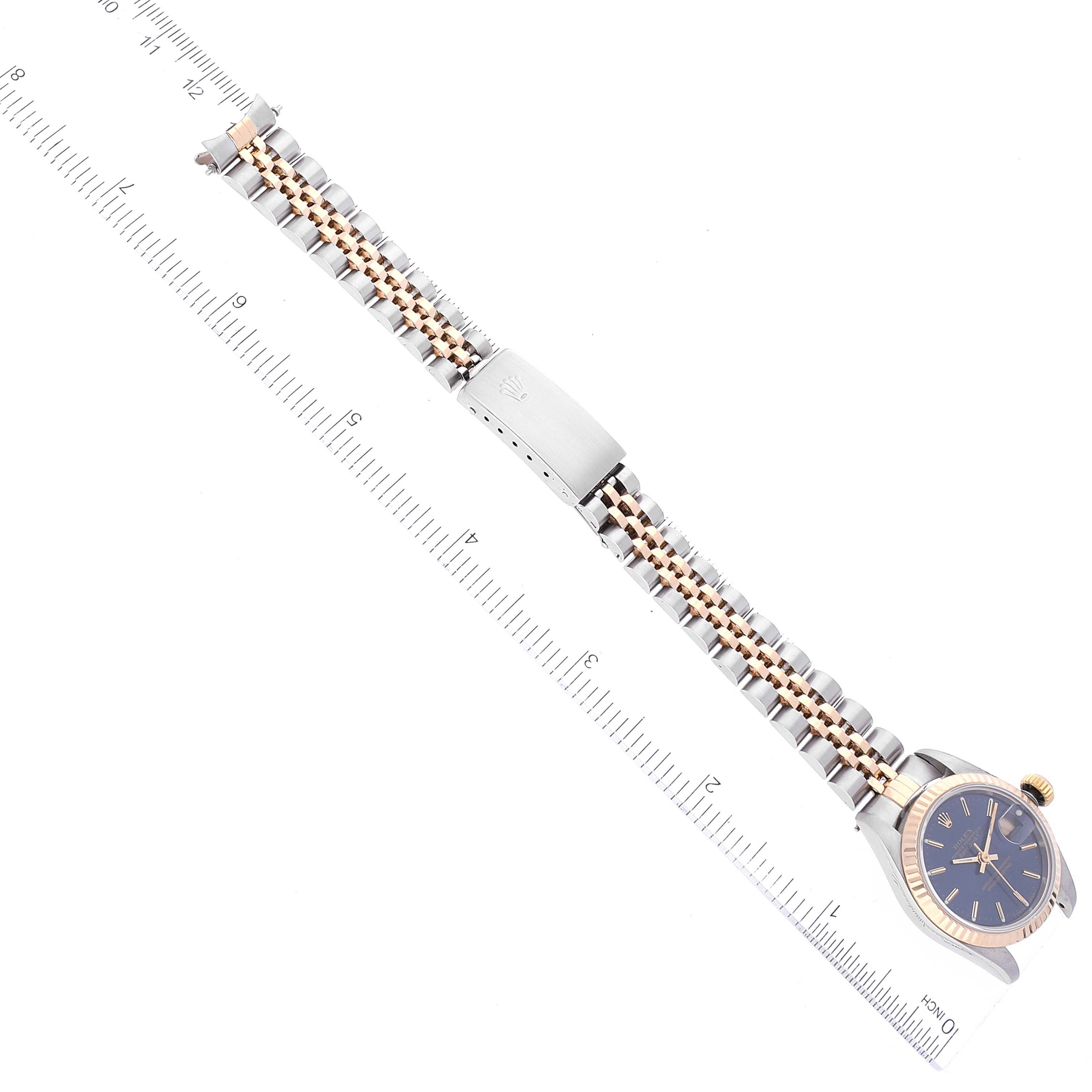 The image shows a top view of a Rolex Datejust 69173 Women's Steel and Gold (two tone) Blue Dial 69173 Women's Steel and Gold (two tone) Blue Dial watch focusing on its band, clasp, and dial against a measurement scale.