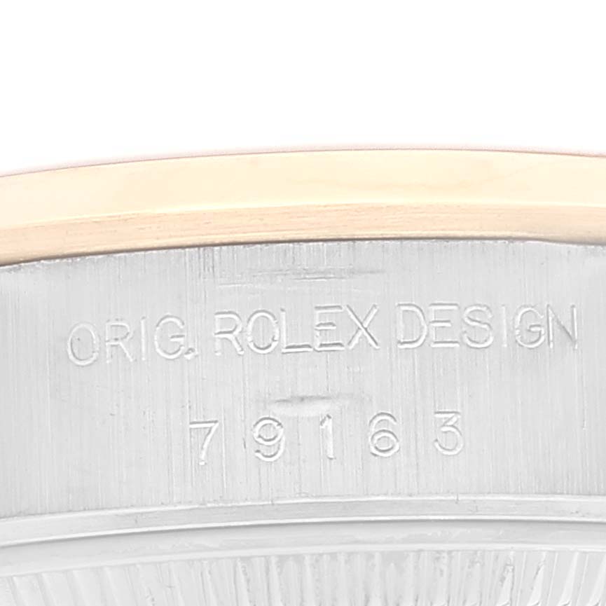 The image shows a close-up of the side of a Rolex Datejust 79163 Women's Steel and Gold (two tone) White Dial 79163 Women's Steel and Gold (two tone) White Dial watch case featuring engravings.