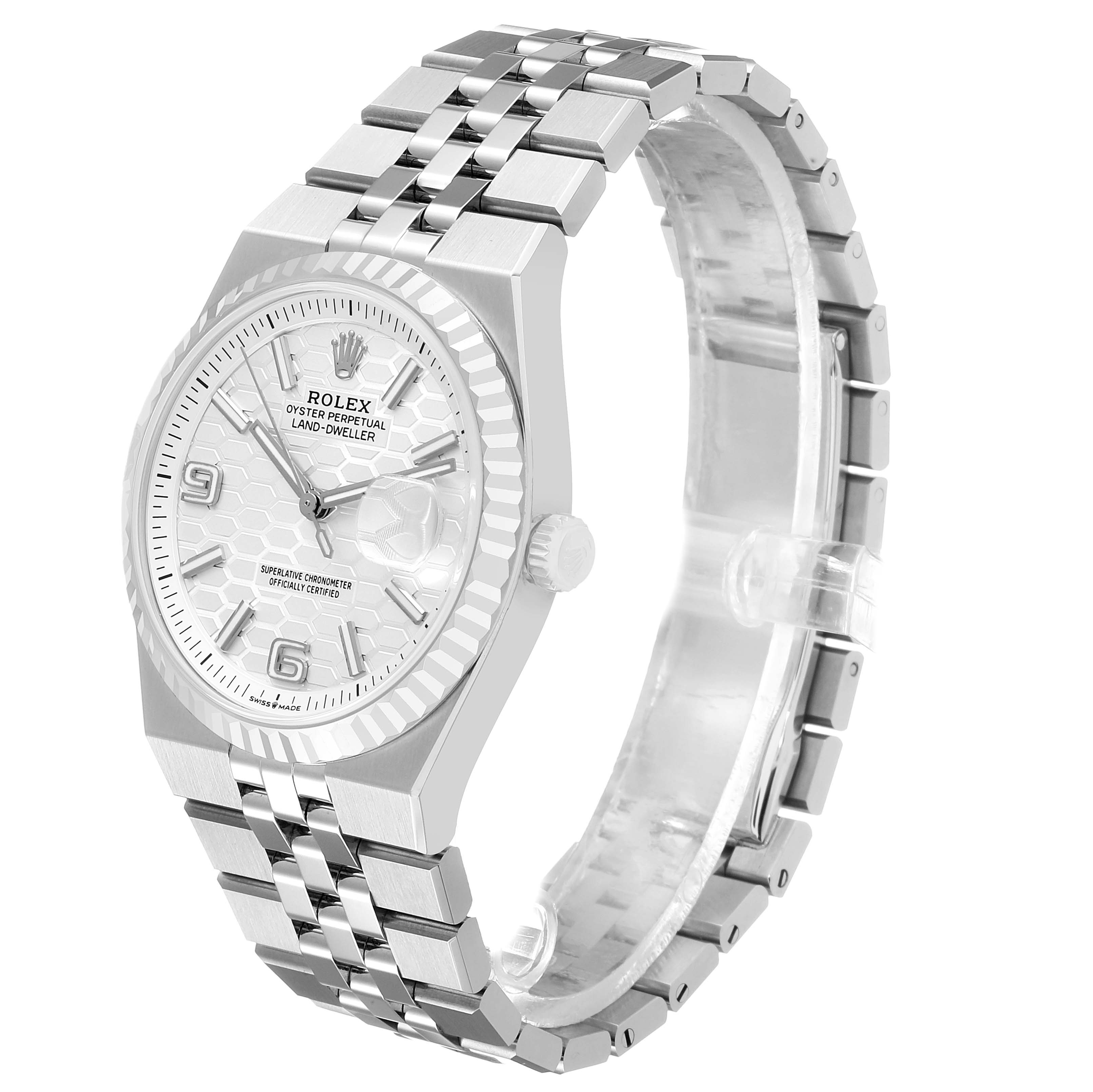 The Rolex Land-Dweller watch is shown at a side angle, highlighting the face, bezel, crown, and bracelet.