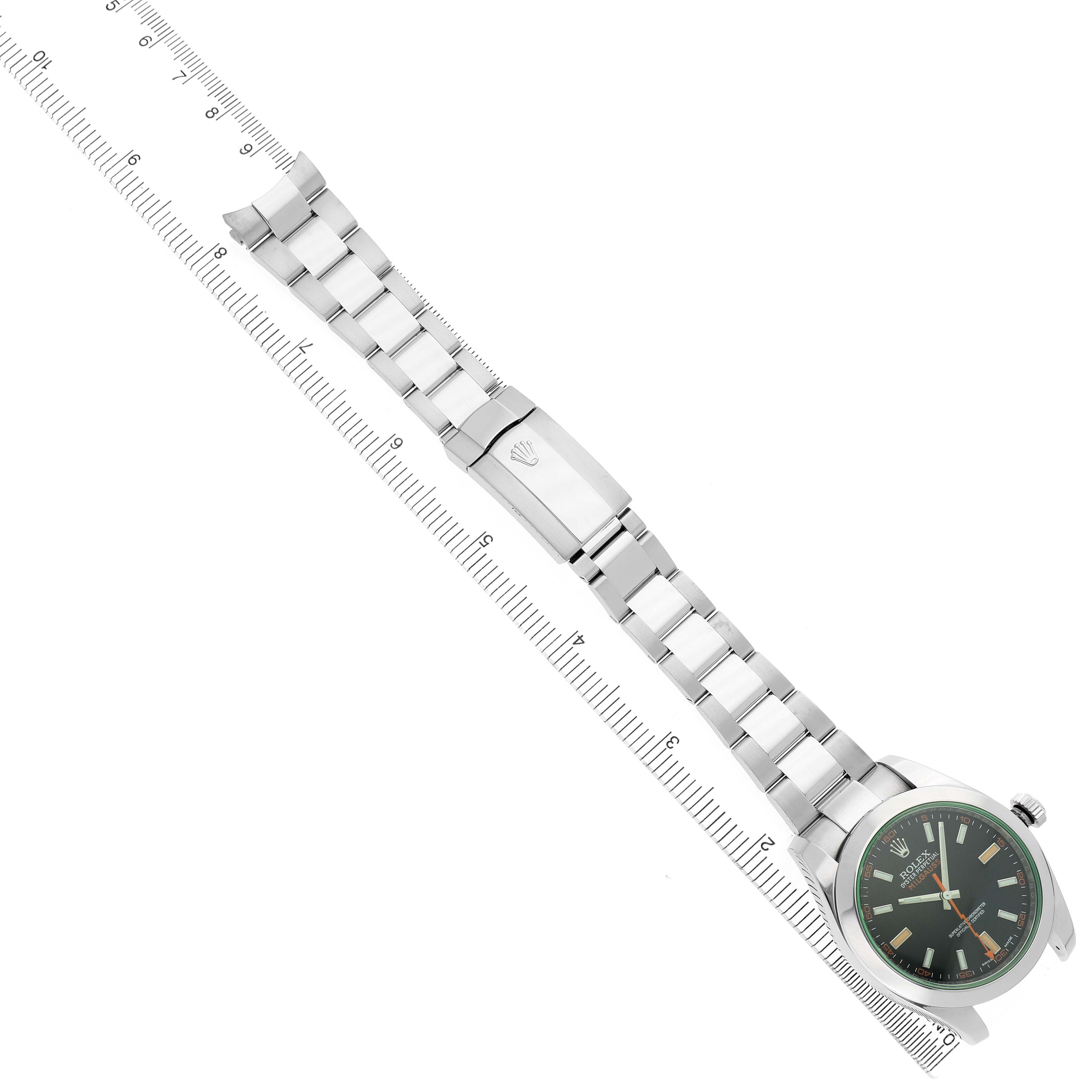 The Rolex Milgauss M116400GV-0001 Men's Stainless Steel Black Dial watch is shown at a slight diagonal angle, displaying its face, bracelet, and clasp alongside a ruler.