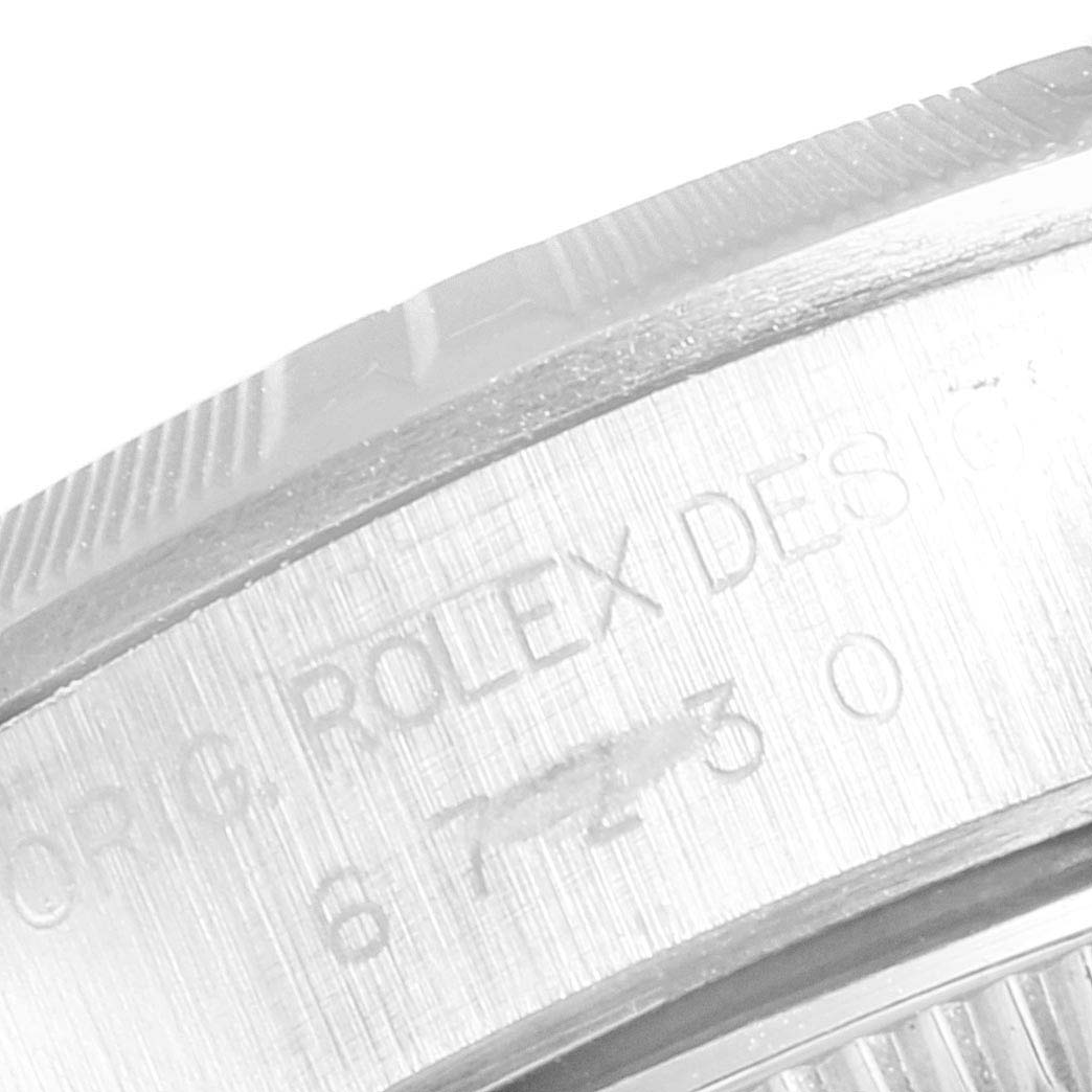 The image shows a partial close-up of the bezel and engraved details on the side of the case of a Rolex Oyster Perpetual 67230 Women
s Stainless Steel Blue Dial 67230 Women
s Stainless Steel Blue Dial watch.