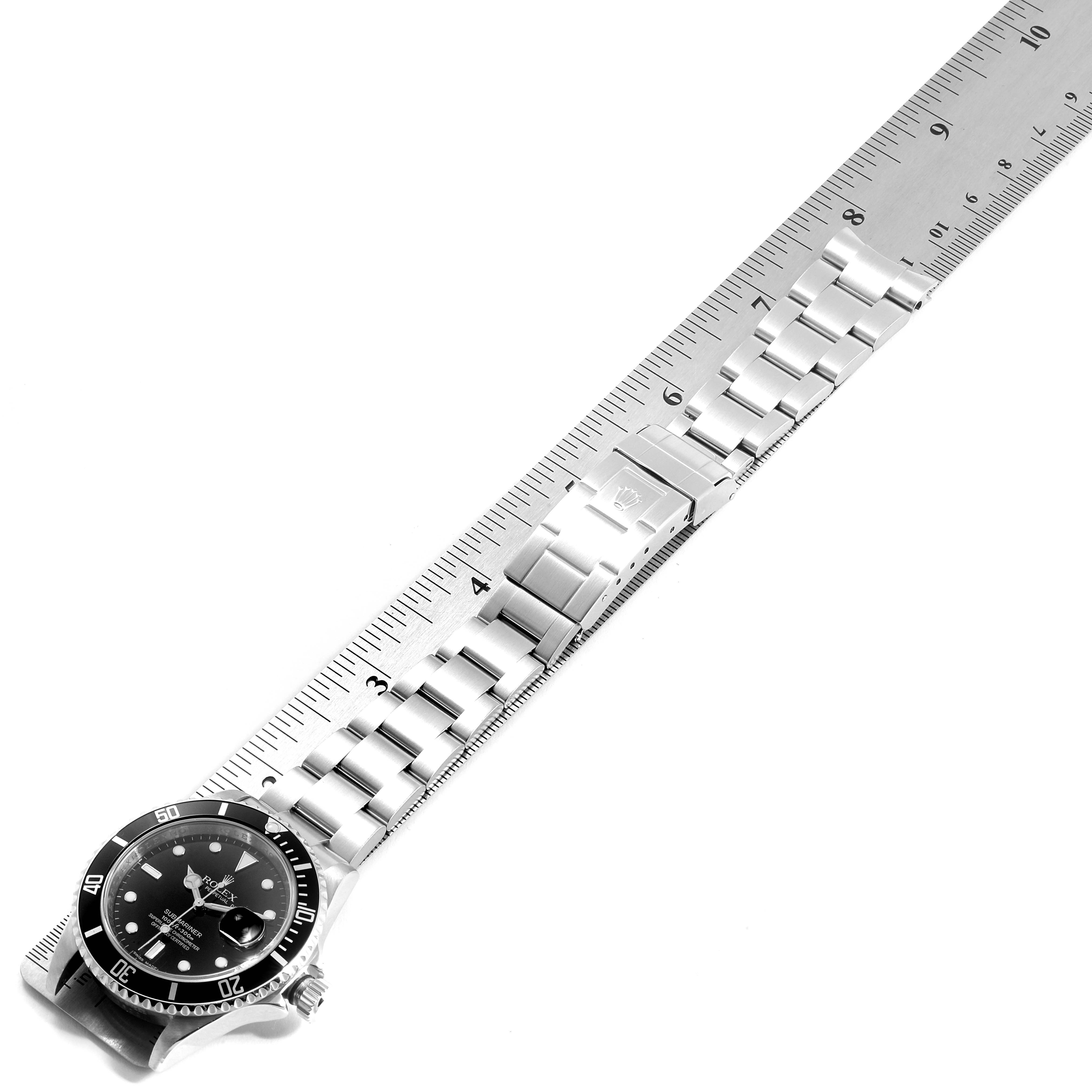 The image shows a side view of the Rolex Submariner 16610 Men
s Stainless Steel Black Dial 16610 Men
s Stainless Steel Black Dial watch with a focus on the band and bezel, placed next to a ruler for measurement.