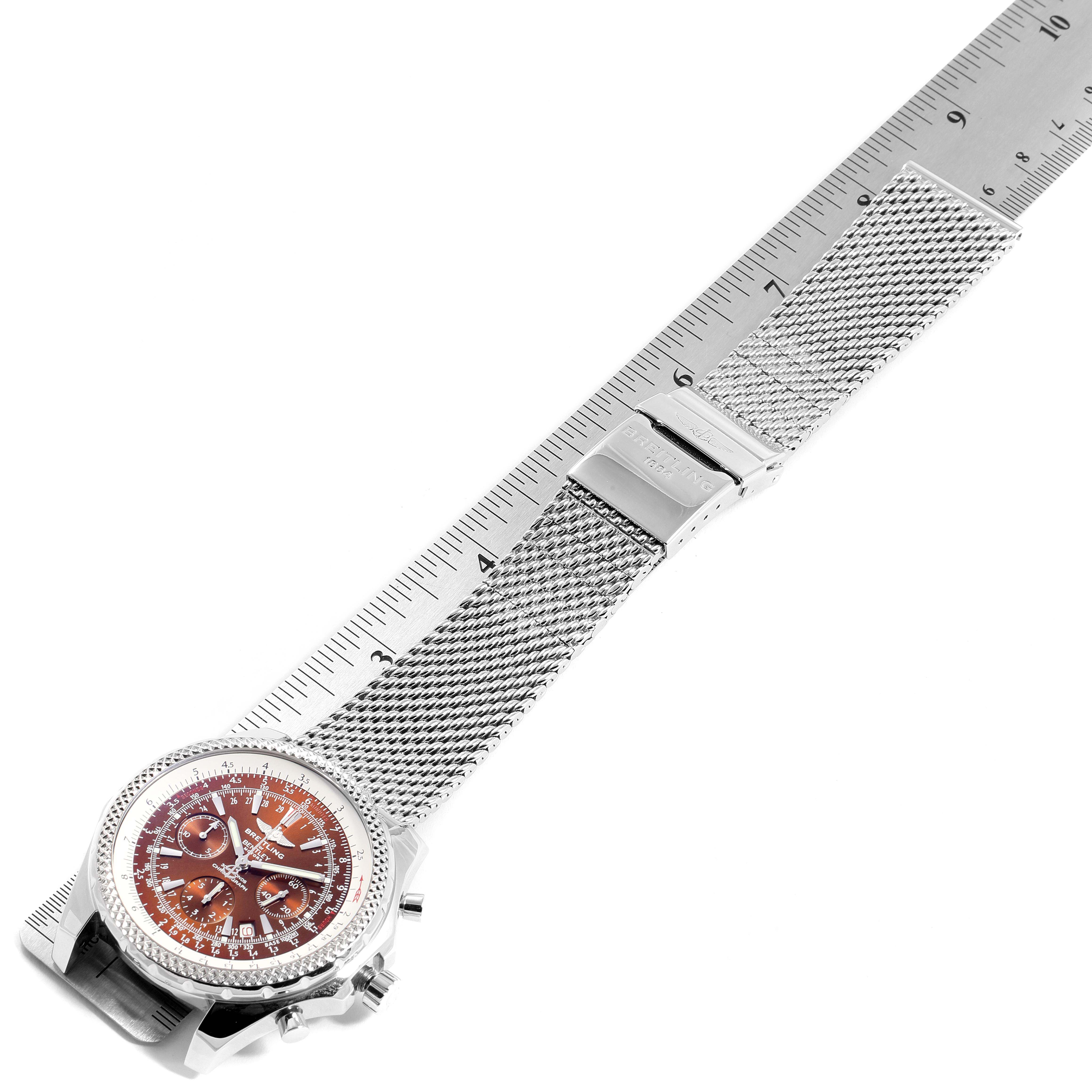 The image shows the Breitling Bentley A25362 Men's Stainless Steel Brown Dial A25362 Men's Stainless Steel Brown Dial model watch laid flat with a mesh strap next to a ruler, displaying the face and buckle.
