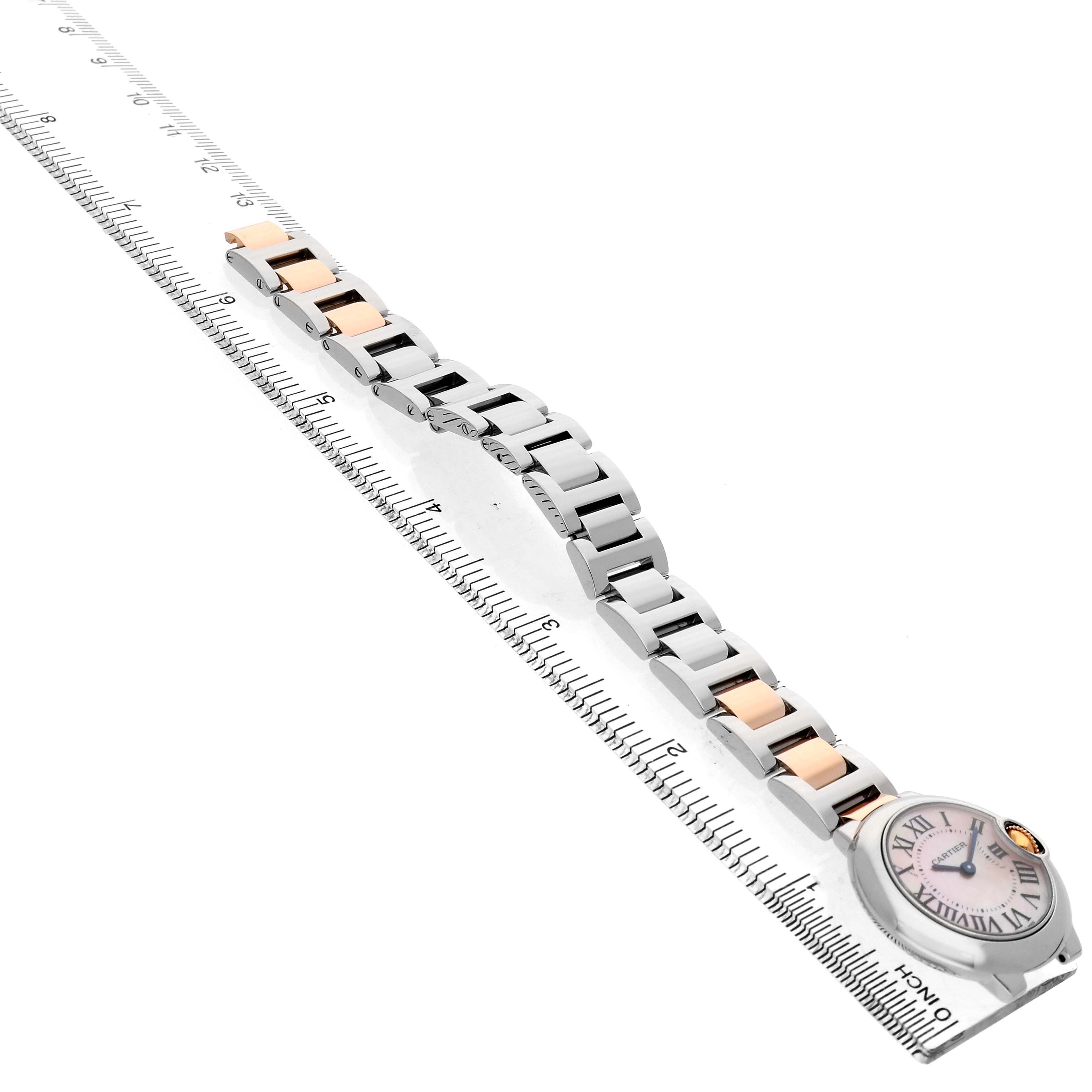 The image shows a Cartier Ballon Bleu W6920034 Women's Steel and Gold (two tone) Mother of Pearl Dial watch at an angle, displaying the full bracelet and face alongside a ruler for scale.